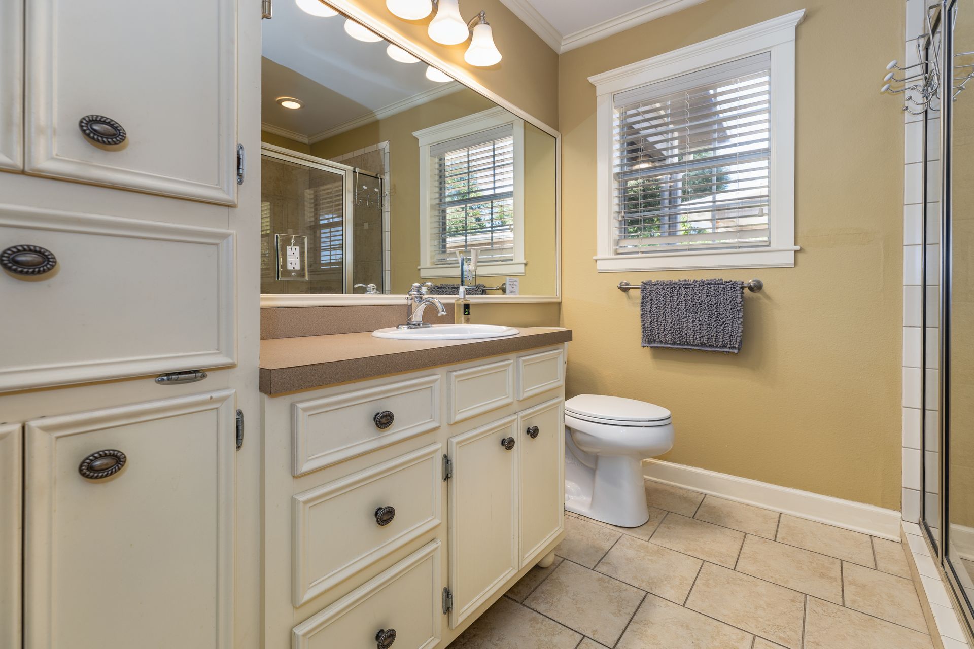 A bathroom with a toilet , sink , mirror and walk in shower.