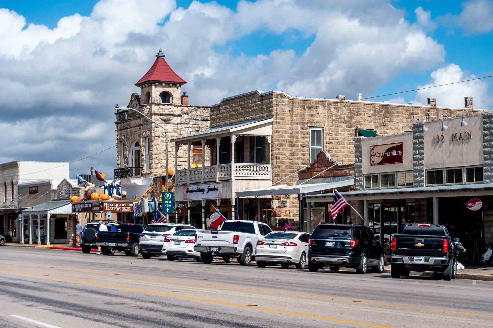 A row of cars are parked in front of a building in a small town.