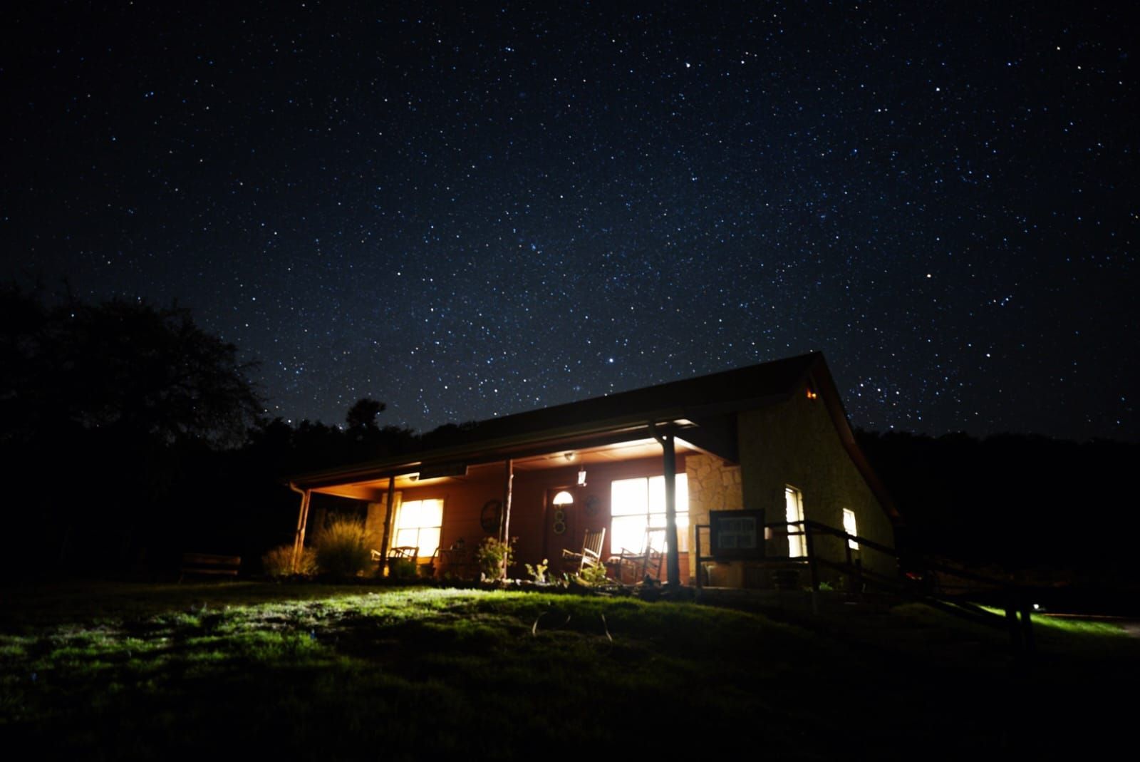 A house is lit up at night under a starry sky