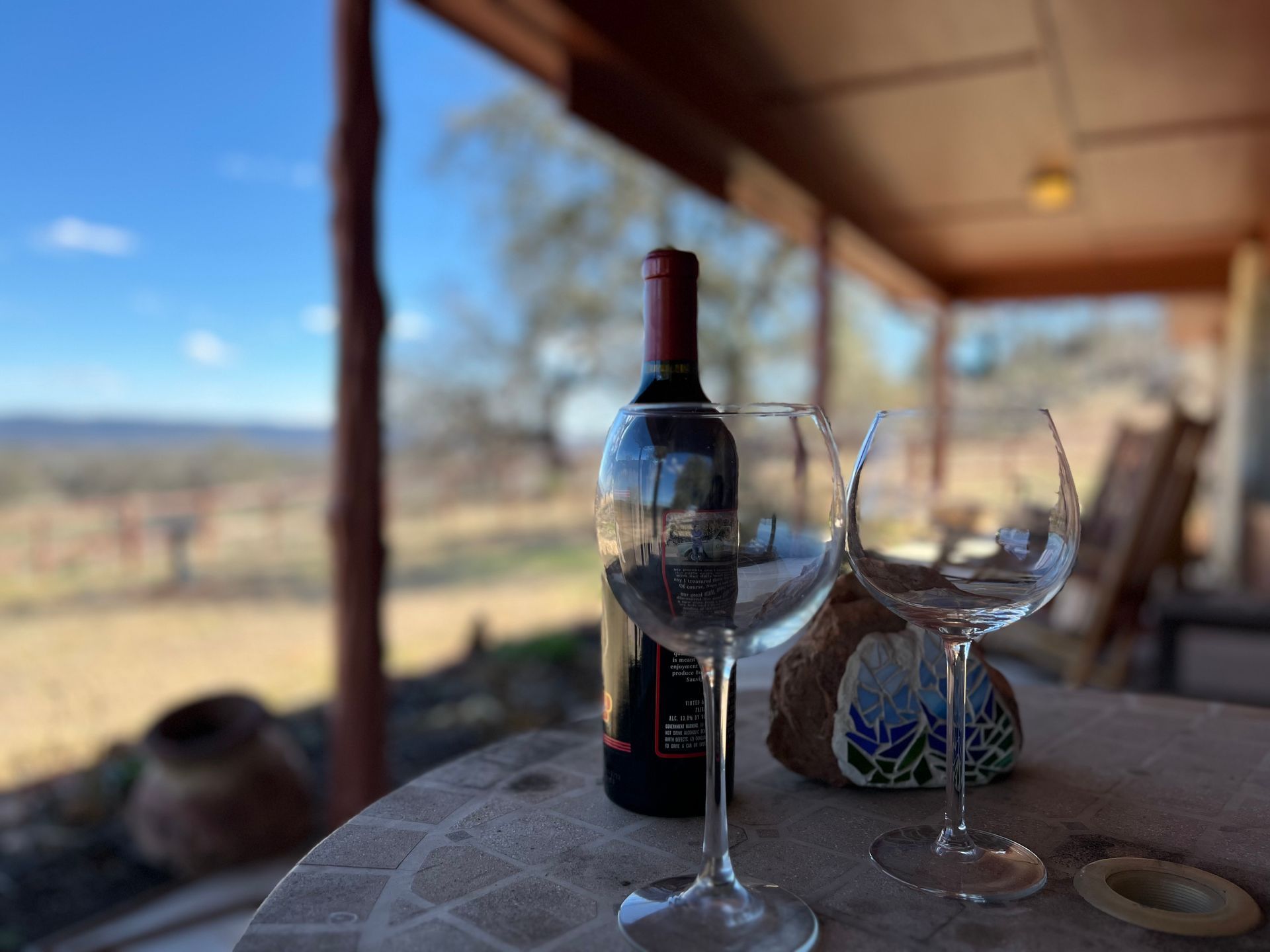 A bottle of wine sits on a table next to two wine glasses.