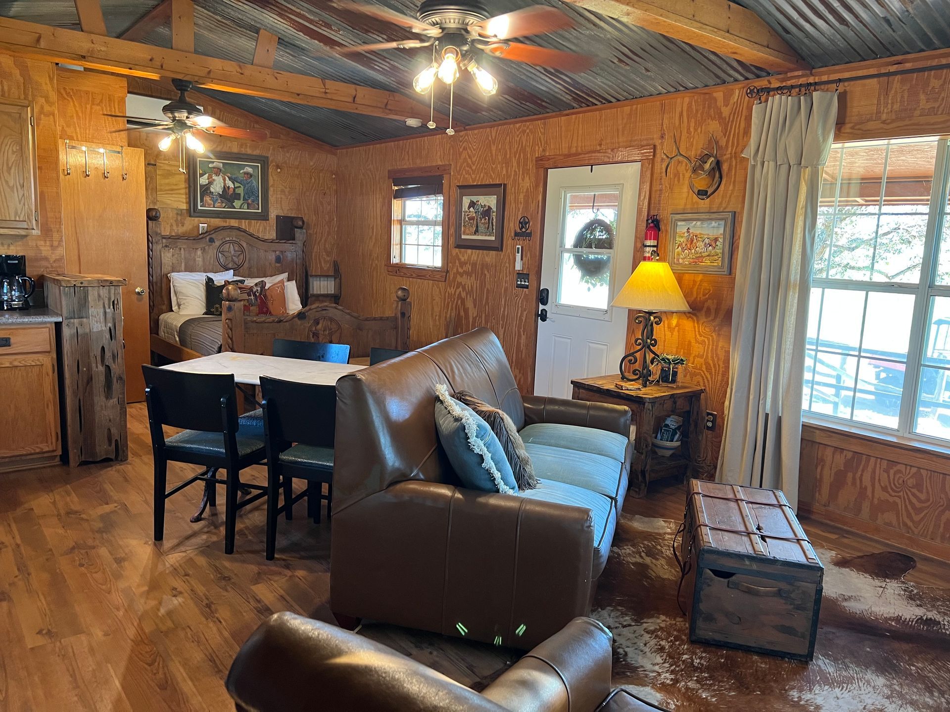 A living room with a couch , chairs , a table and a ceiling fan.