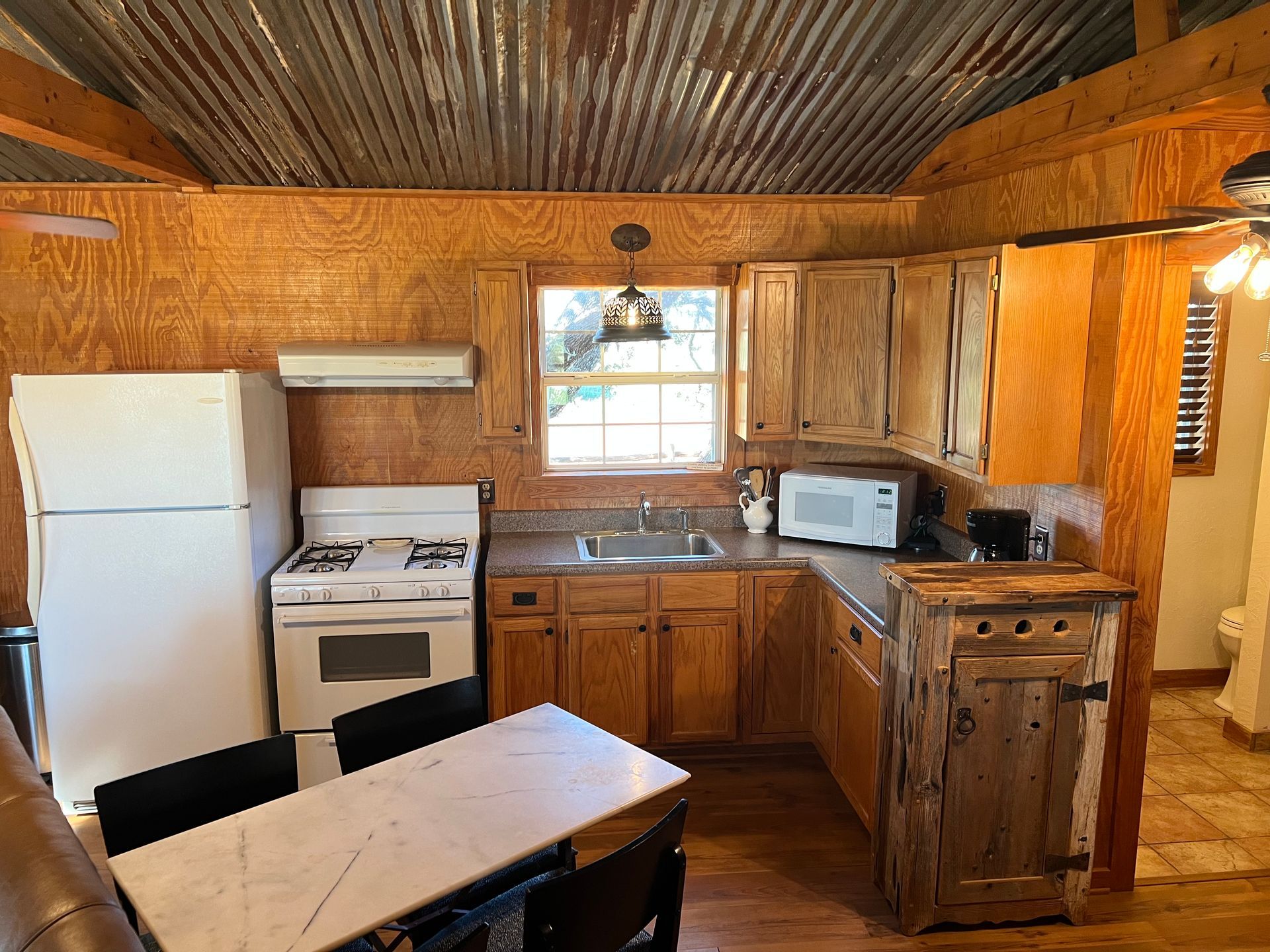 A kitchen with a stove , refrigerator , sink , and table.