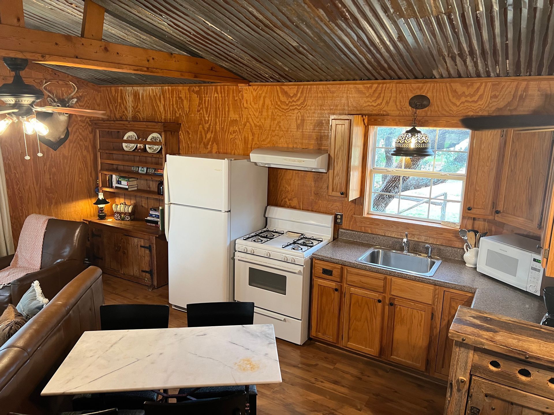 A kitchen with a stove , refrigerator , sink and table.