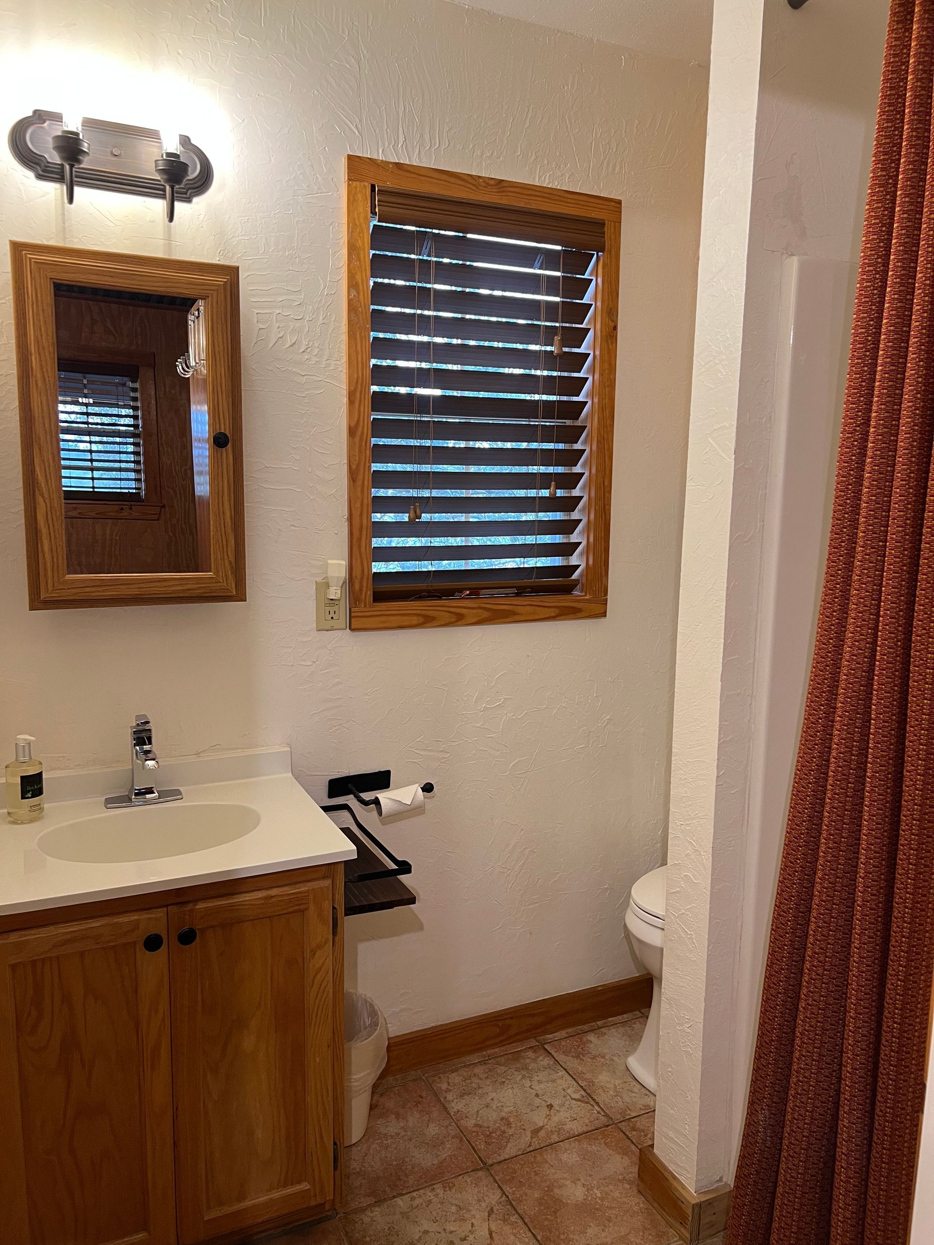 A bathroom with a sink , toilet , mirror and shower.