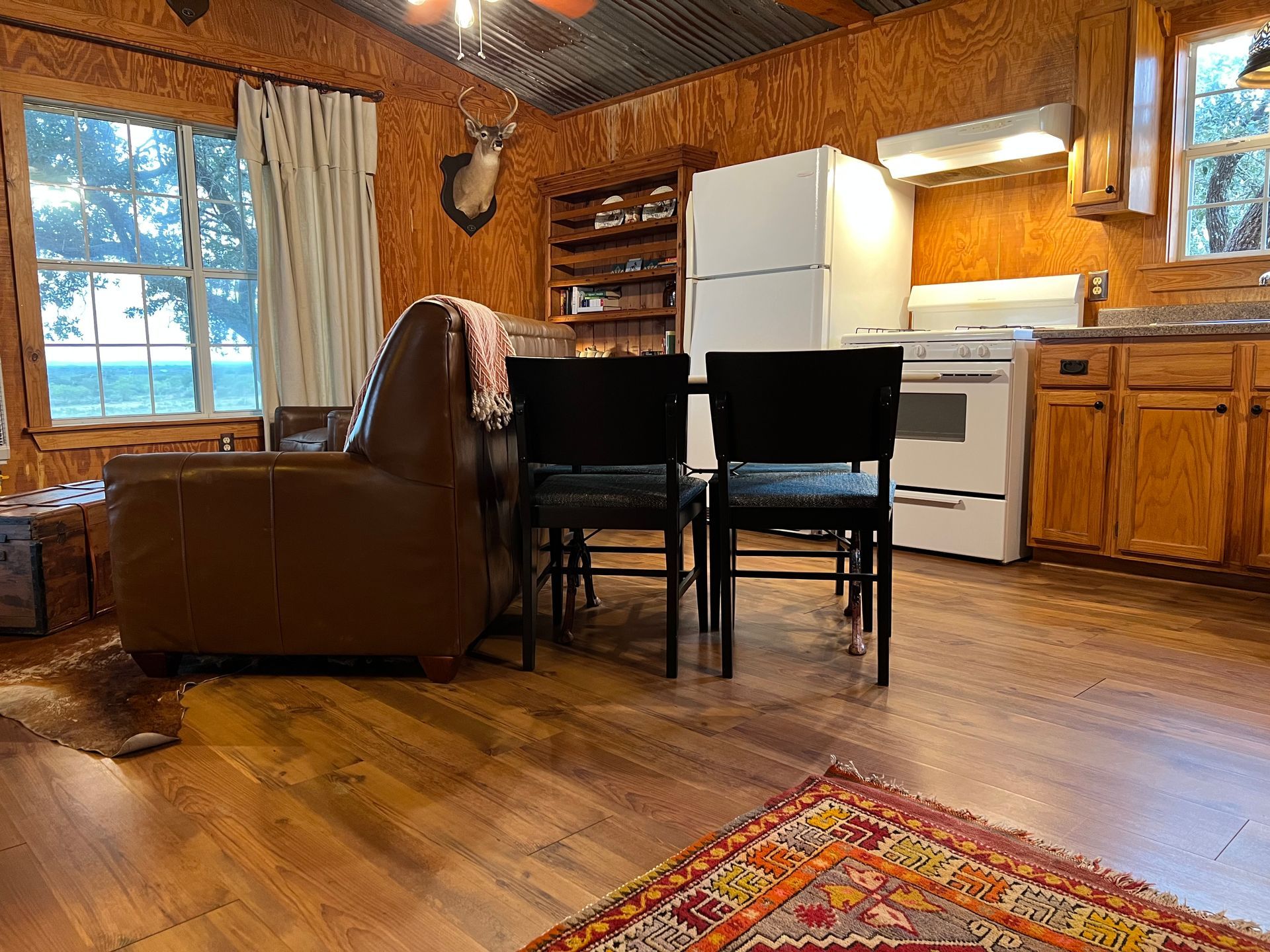 A living room with a dining table , chairs , and a refrigerator.