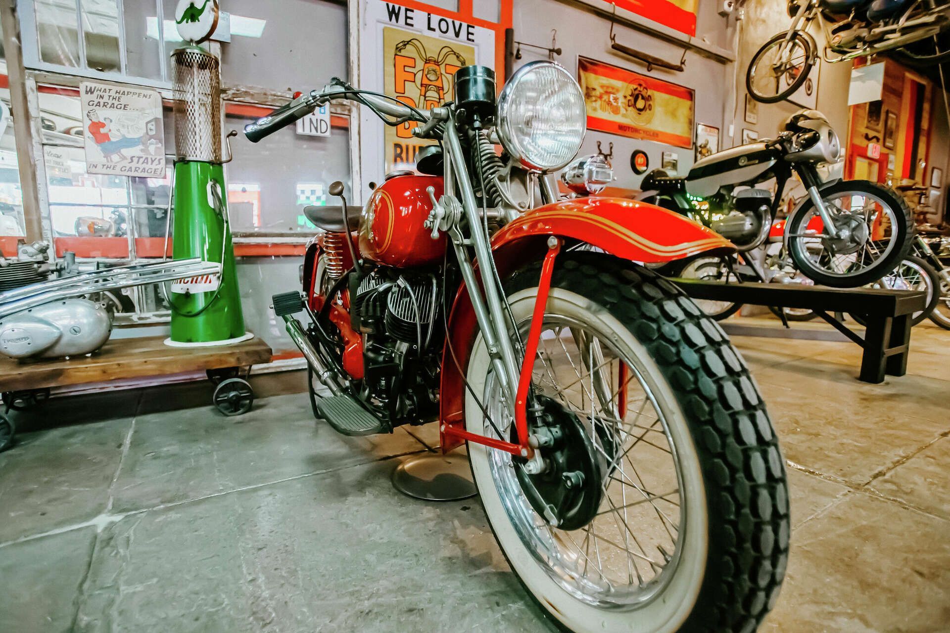 A red motorcycle with white tires is parked in a garage.