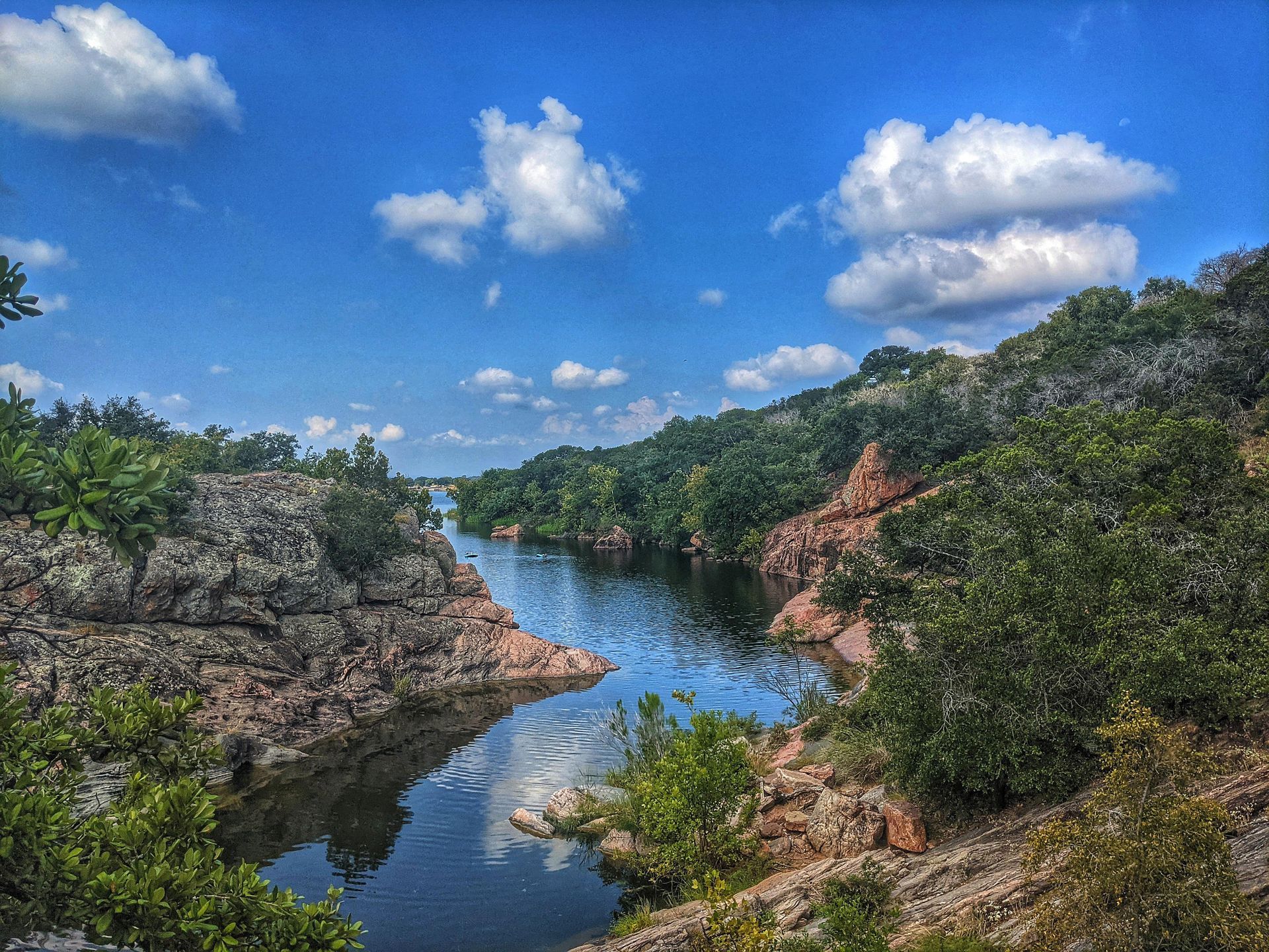 A river surrounded by trees and rocks on a sunny day.