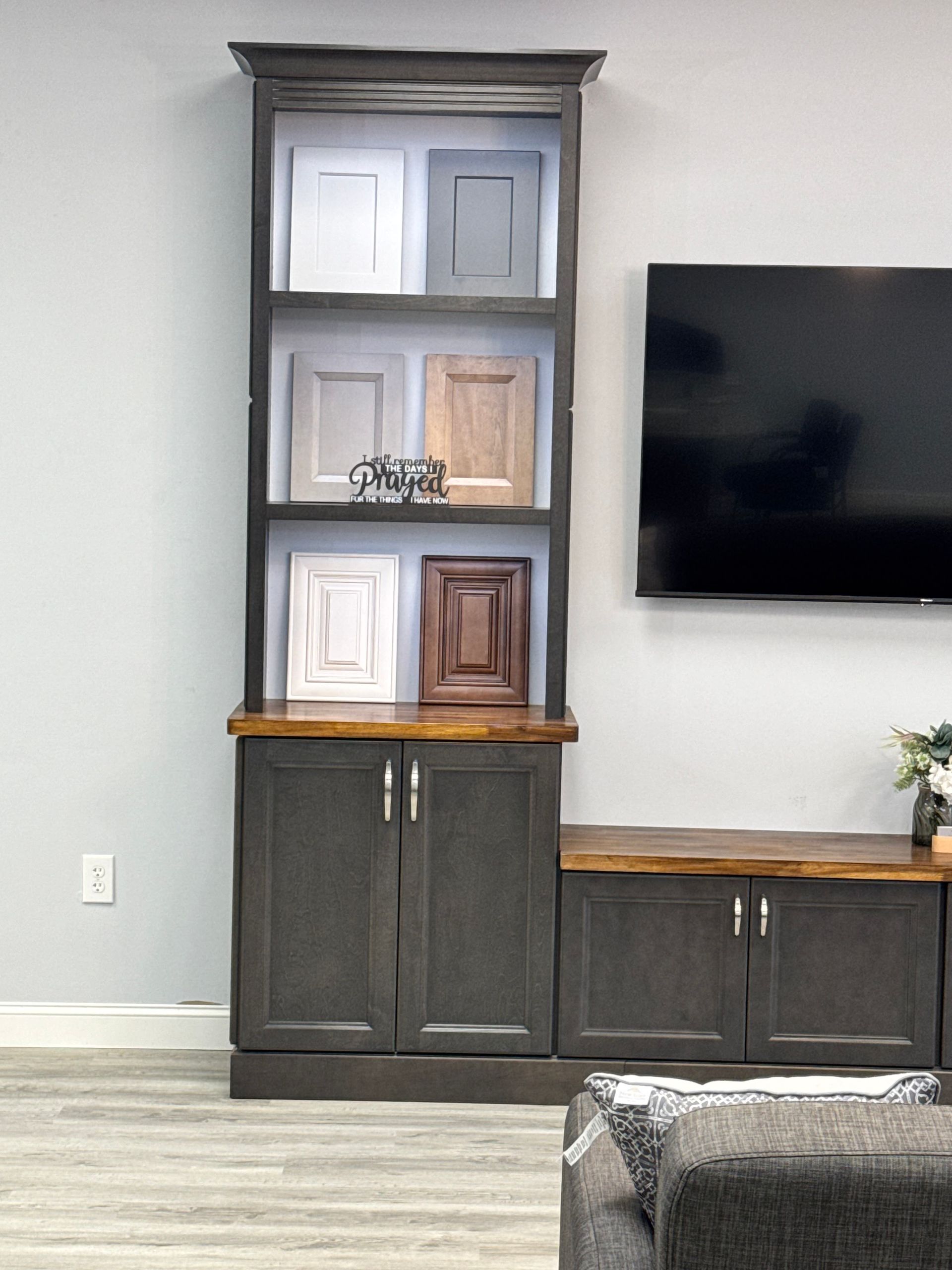 Tall cabinet with paint color samples and a TV on a gray wall.