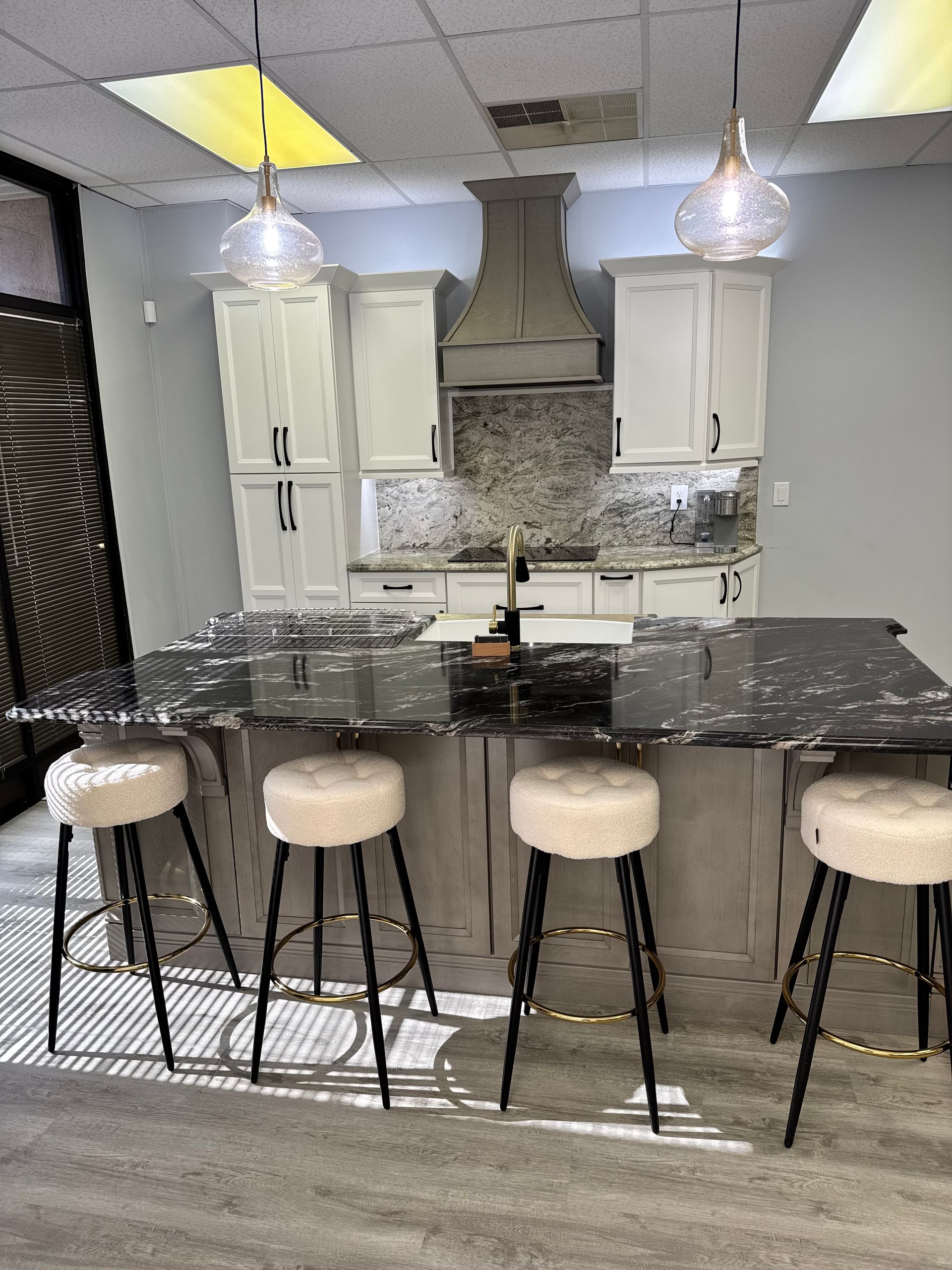 Kitchen with island, black countertop, cream cabinets, and bar stools. Two pendant lights hang overhead.