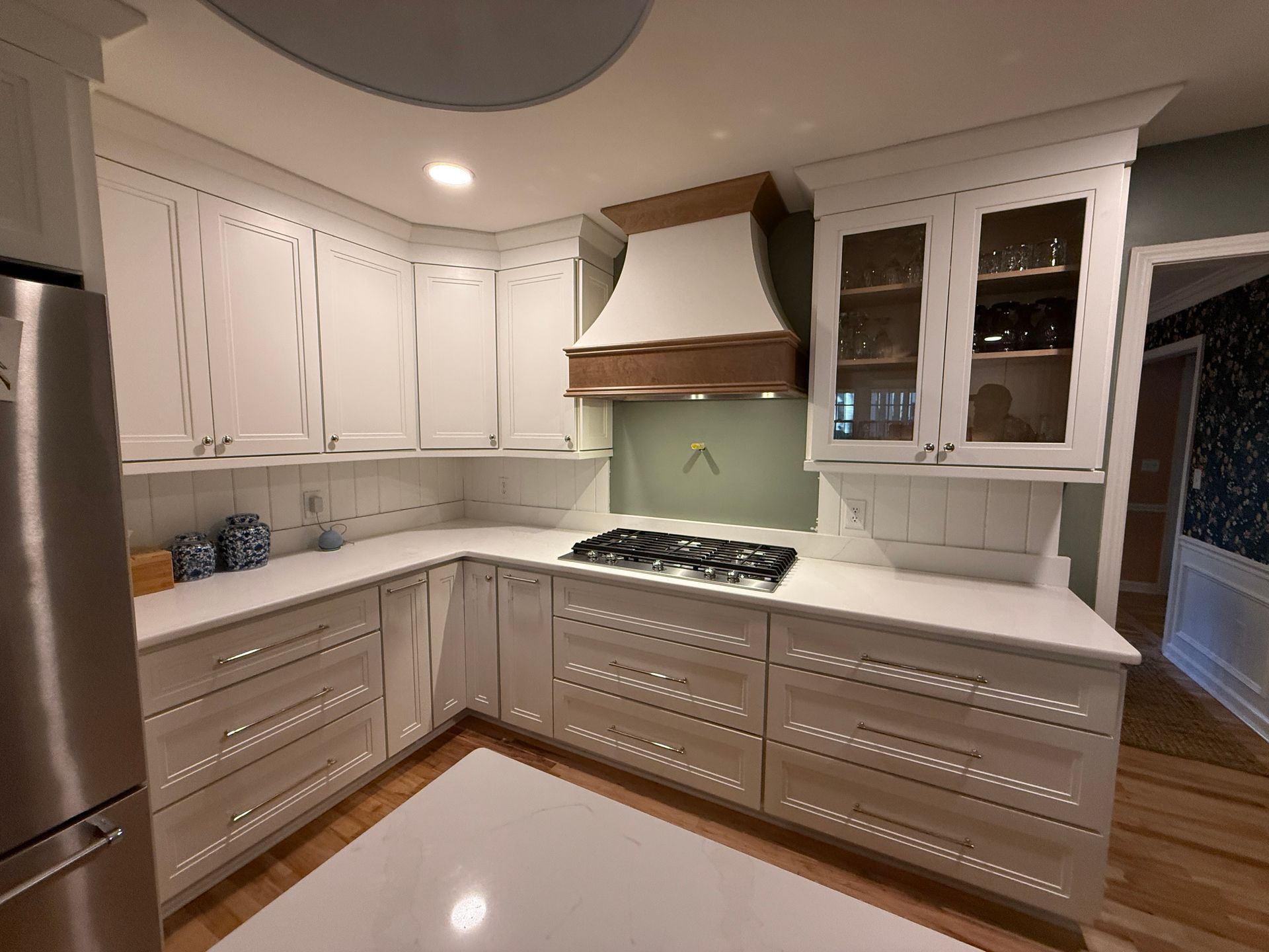 Kitchen with white cabinets, dark countertops, and mosaic tile backsplash; orange wall.