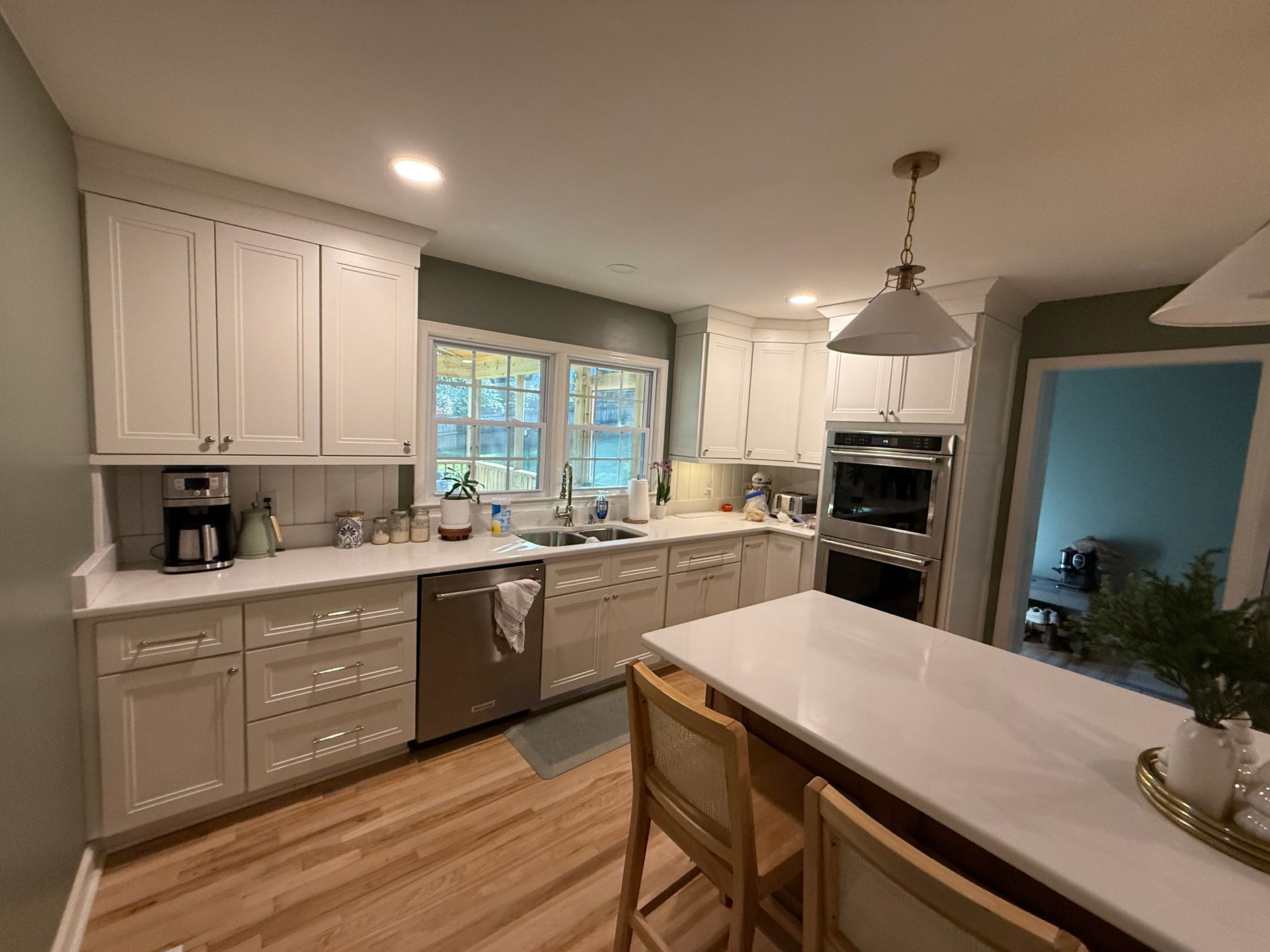 Kitchen with white cabinets, stainless steel appliances, and a white countertop island.