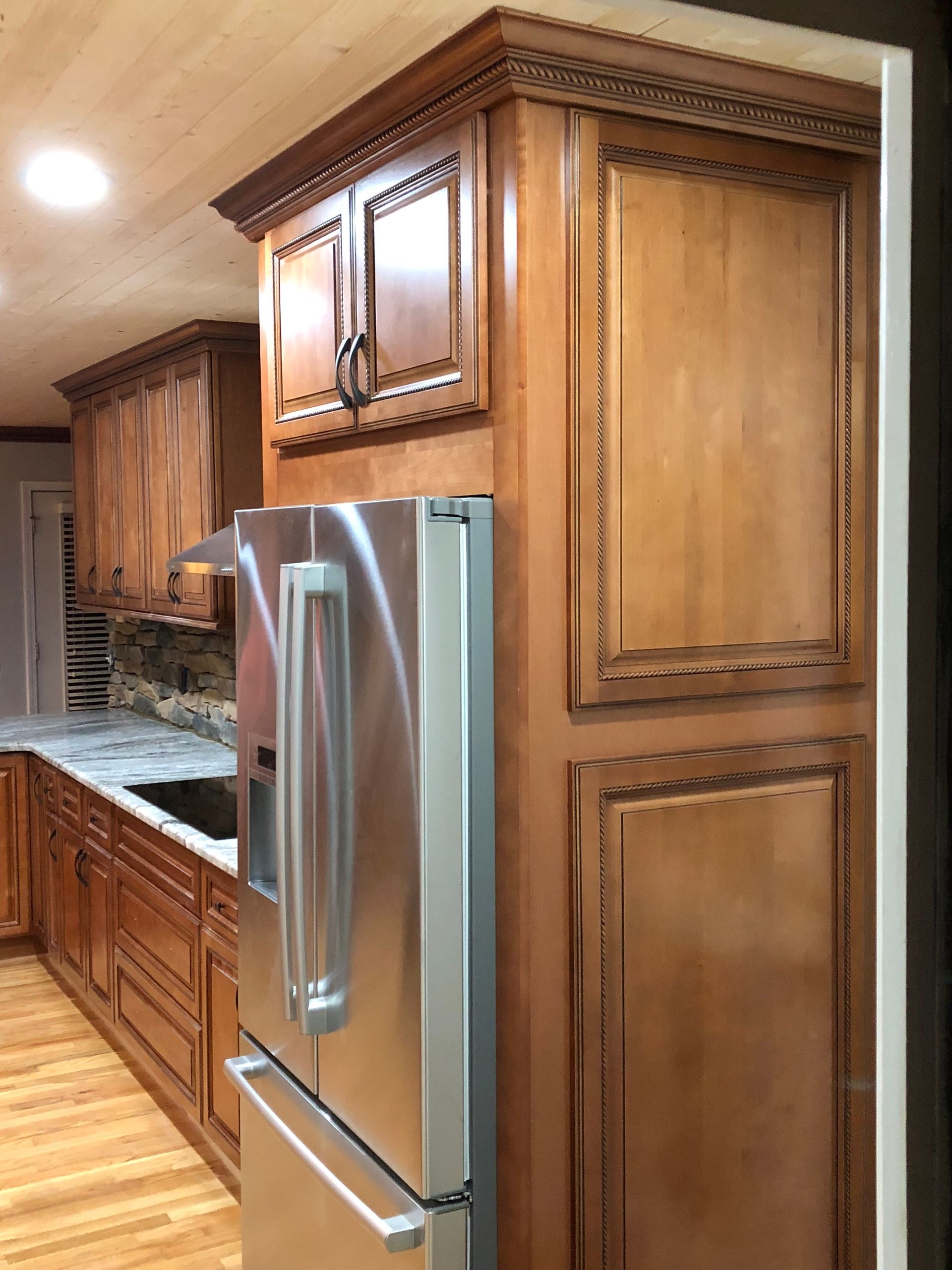 Stainless steel refrigerator next to wooden kitchen cabinets.