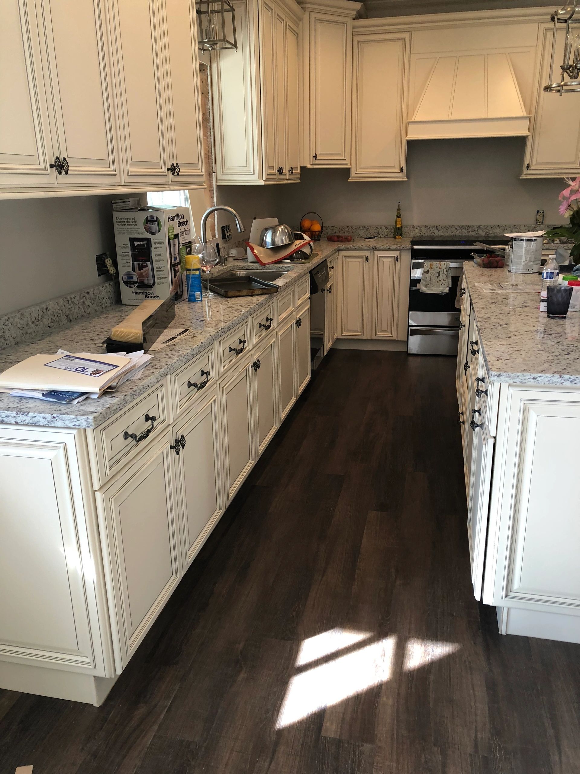 A kitchen with white cabinets, dark wood floors, and granite countertops.