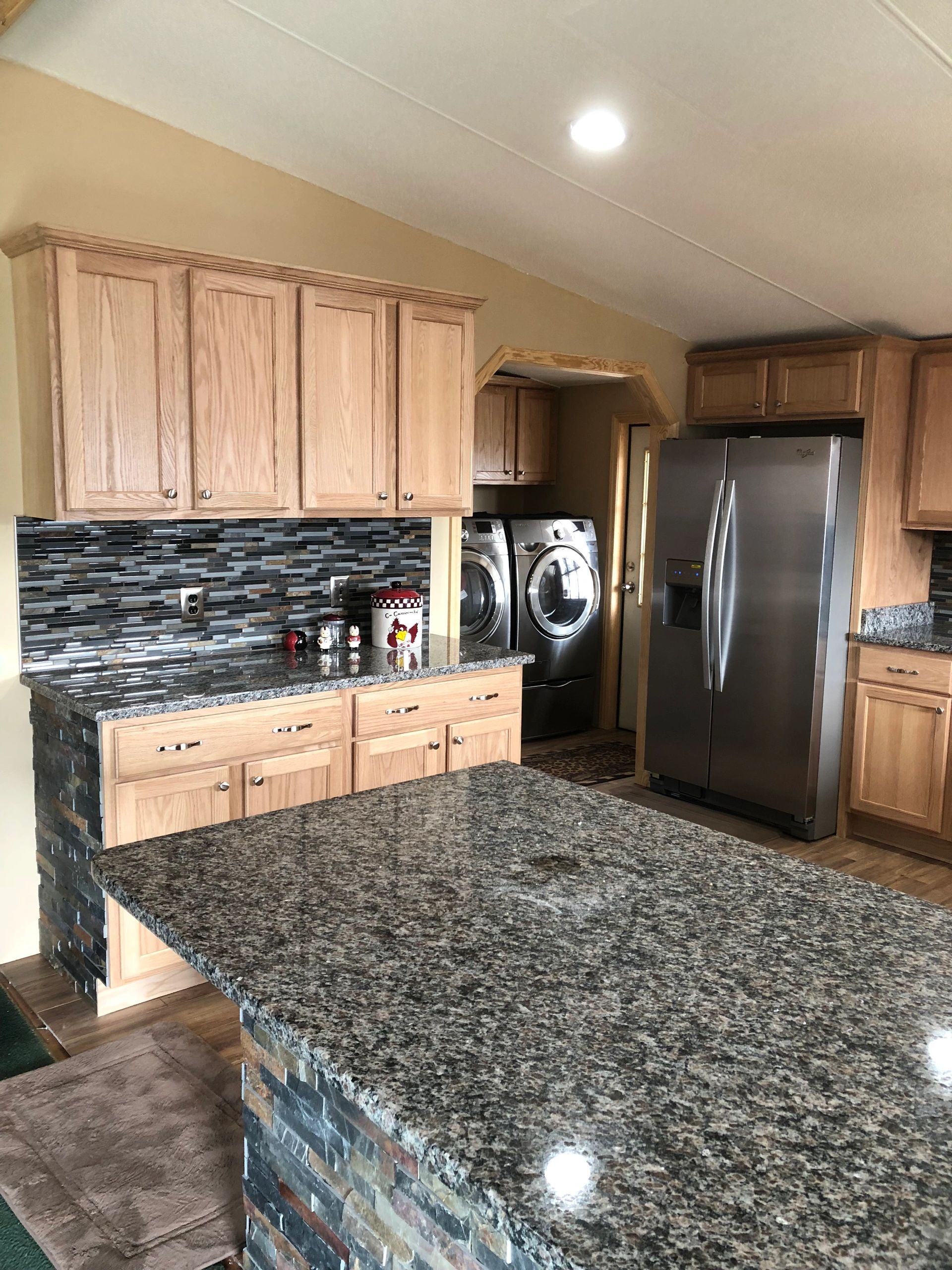Kitchen with black granite island, white cabinets, and four cushioned stools.