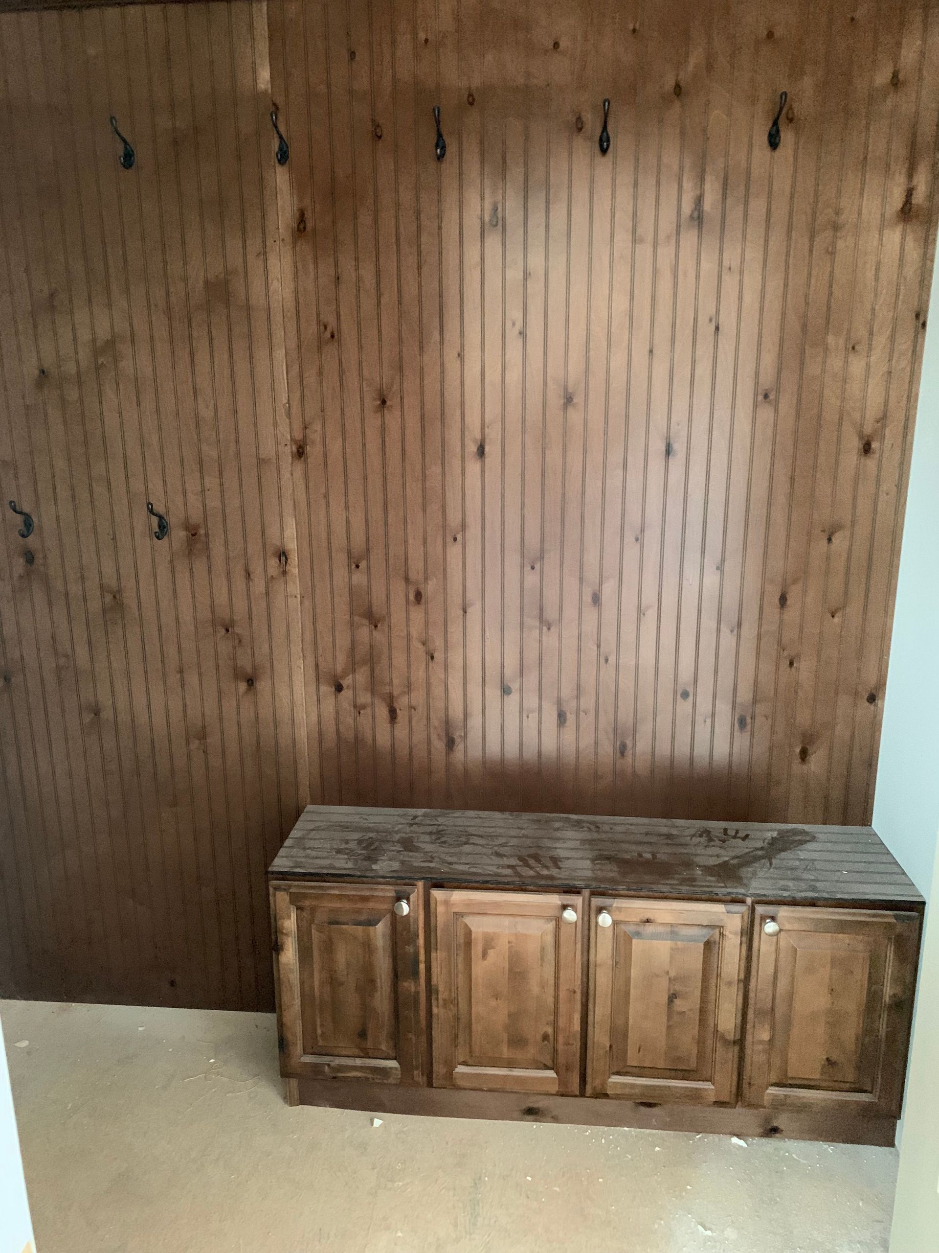 Wooden cabinets below a wall with vertical wooden paneling.