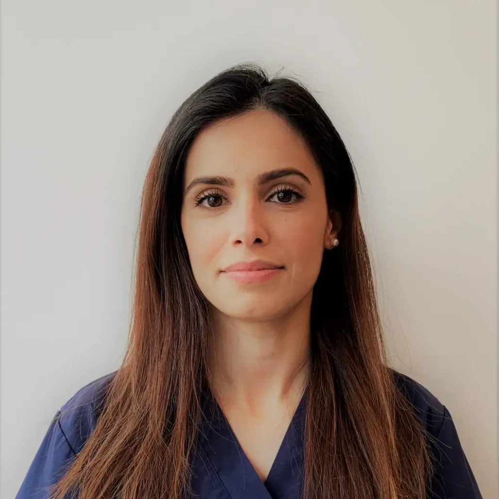 Tannlege Christian med briller og skjegg, iført blå skjorte og medisinsk maske, smiler til kameraet.