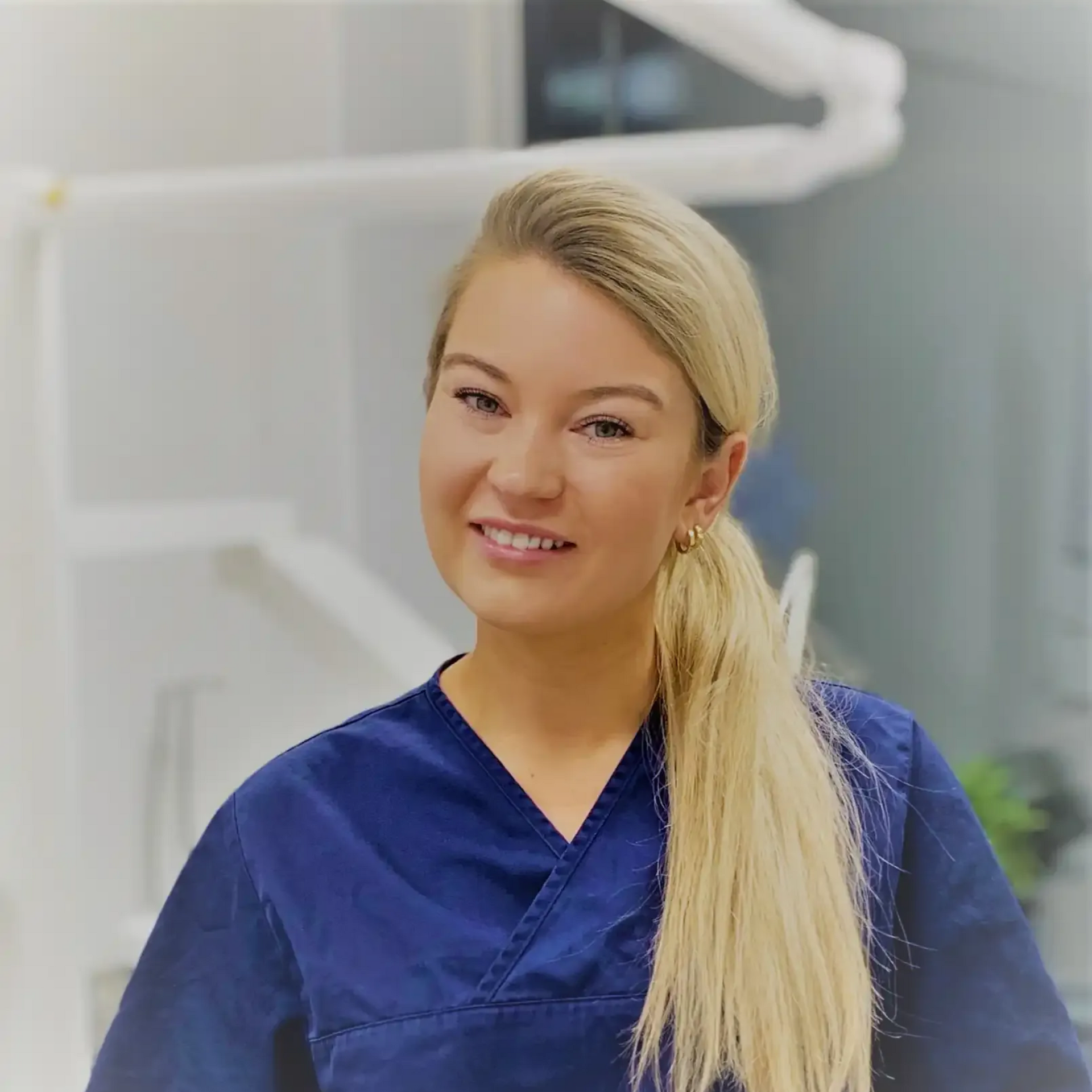 Tannlege Christian med briller og skjegg, iført blå skjorte og medisinsk maske, smiler til kameraet.