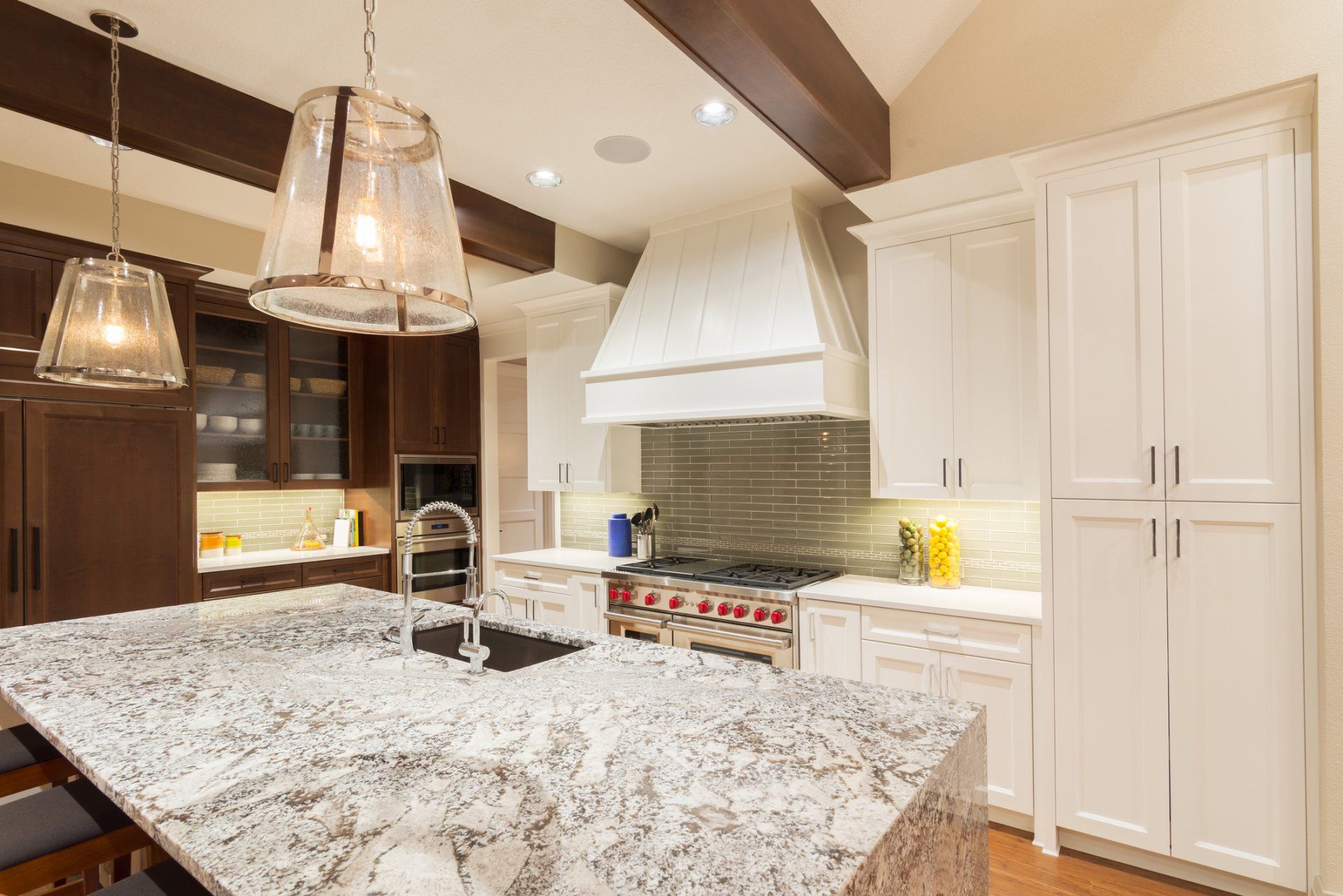 A kitchen with granite counter tops , white cabinets , stainless steel appliances and a large island.