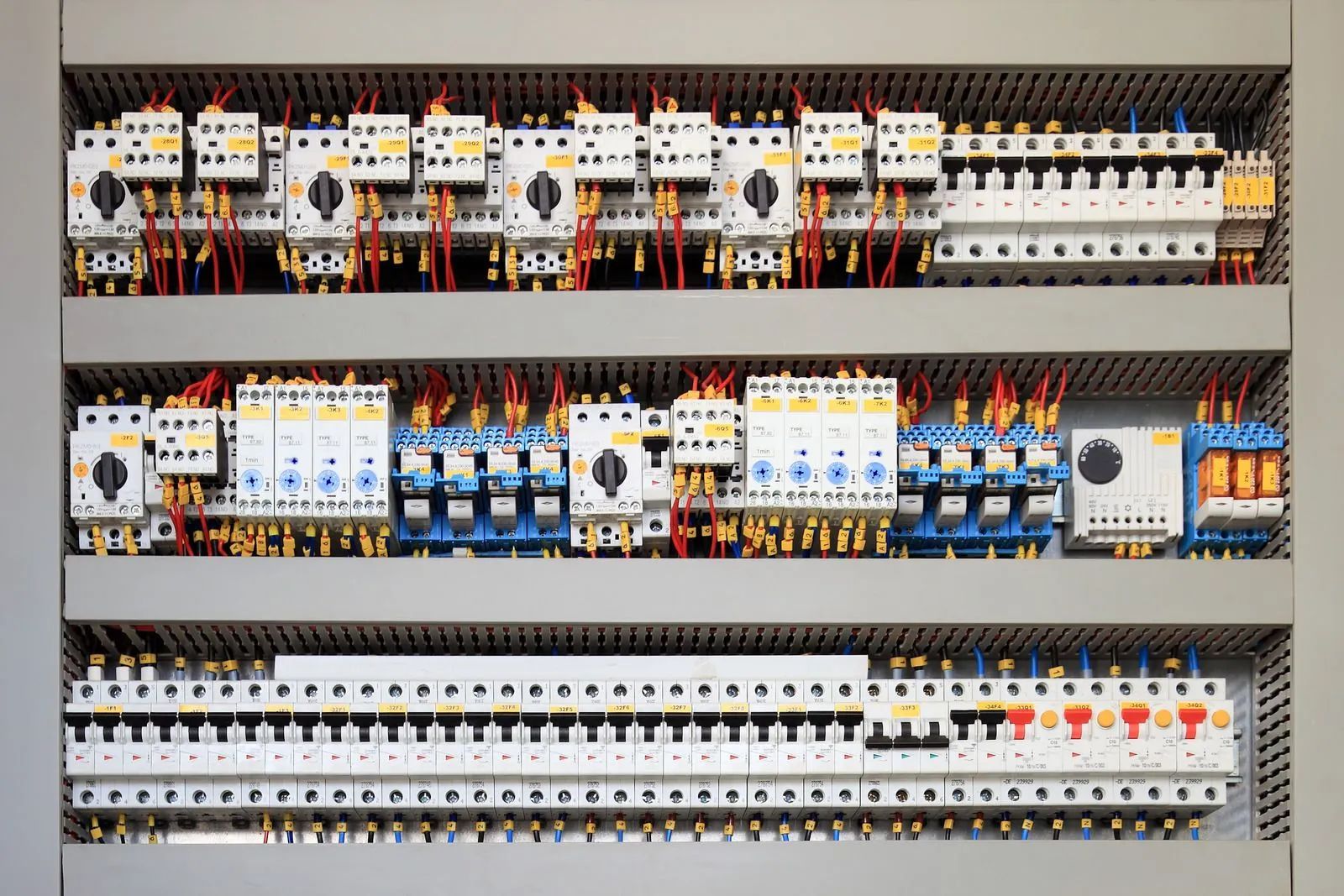 Electrical control panel with rows of circuit breakers, wiring, and other components.