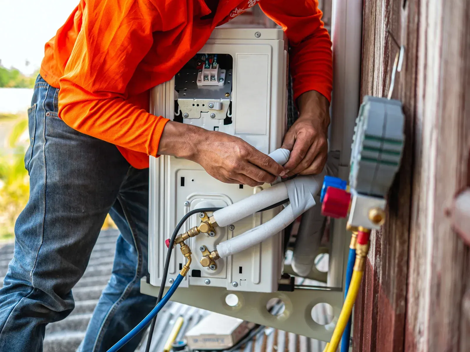 A man is working on an air conditioner outside of a building.