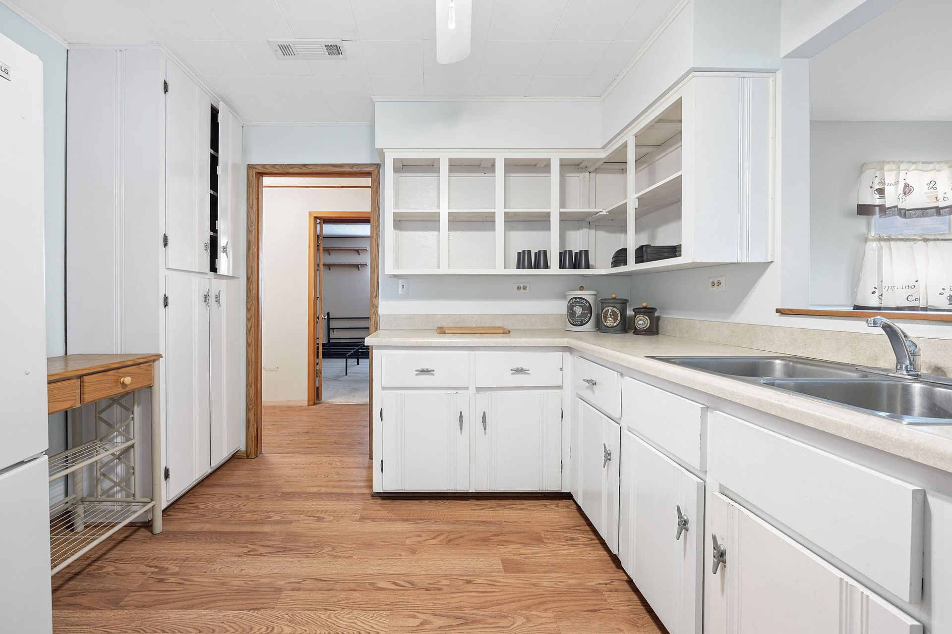 A kitchen with white cabinets , a sink , and a refrigerator.