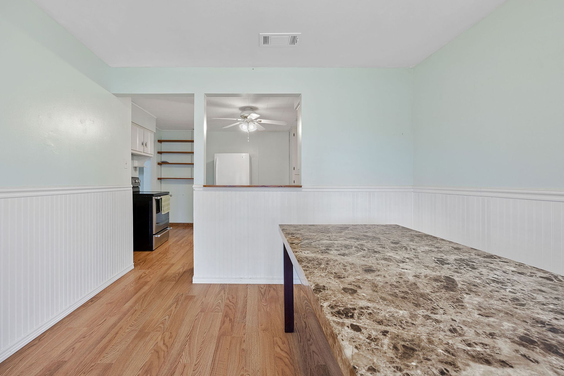 An empty dining room with a long table and a ceiling fan.