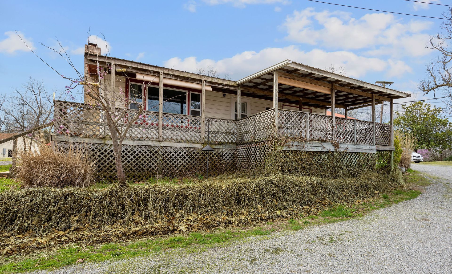 A house with a porch is sitting on top of a gravel hill.