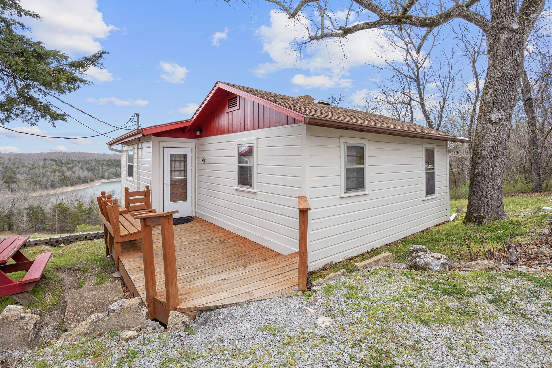 A small white house with a red roof and a wooden deck.