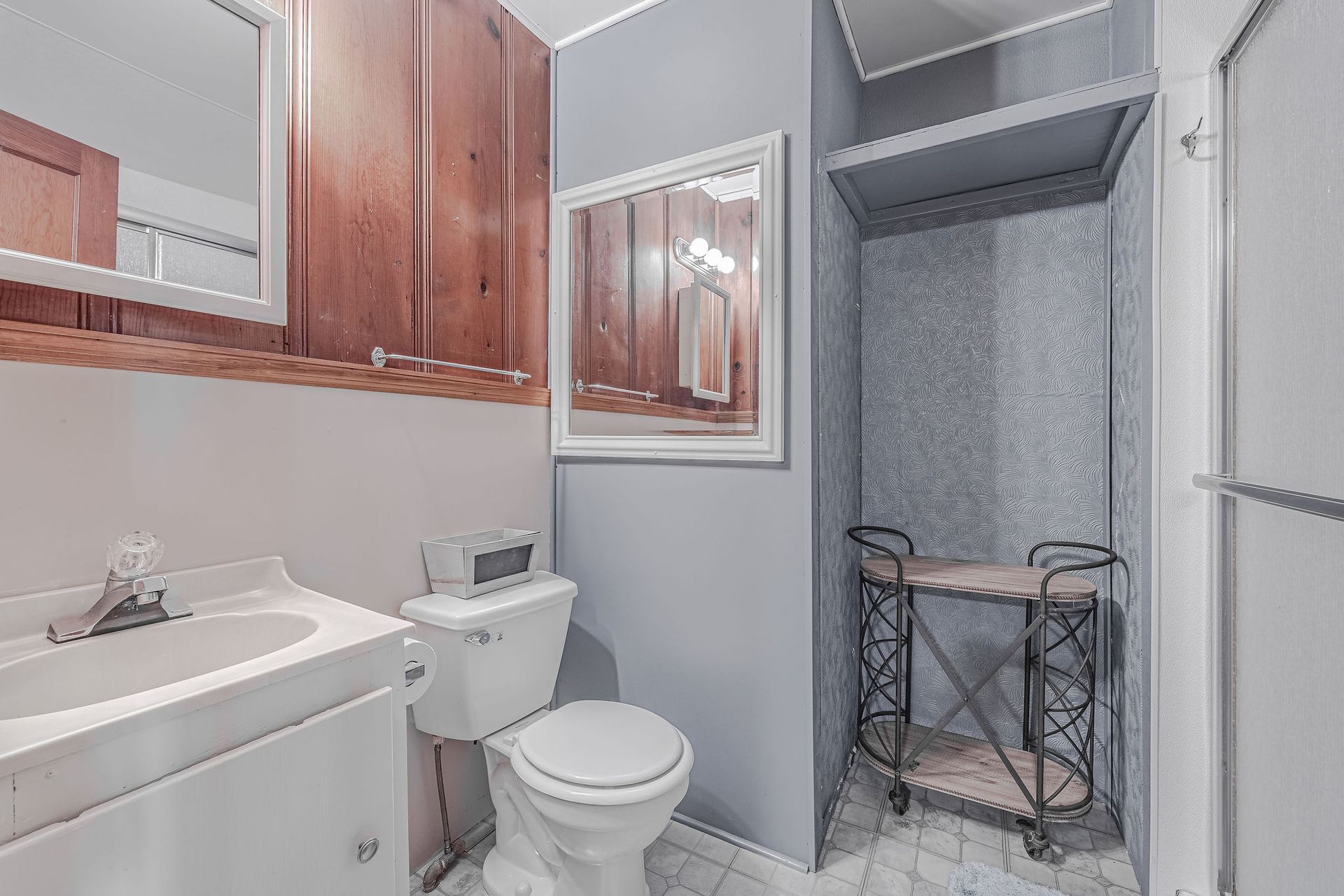 A bathroom with a toilet , sink and mirror.