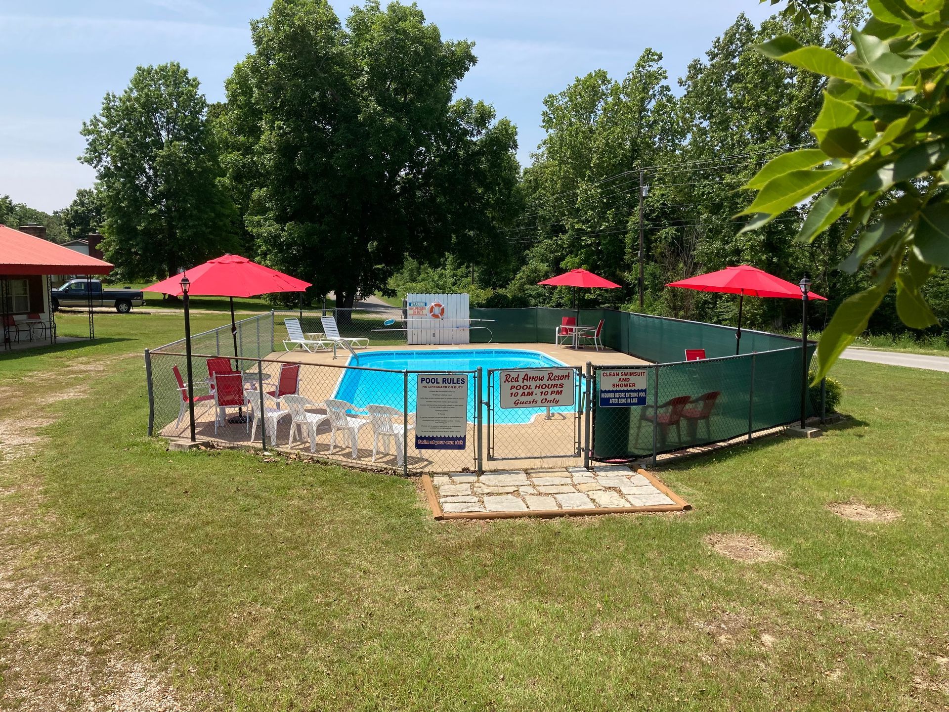 A large swimming pool surrounded by chairs and umbrellas in a grassy area.