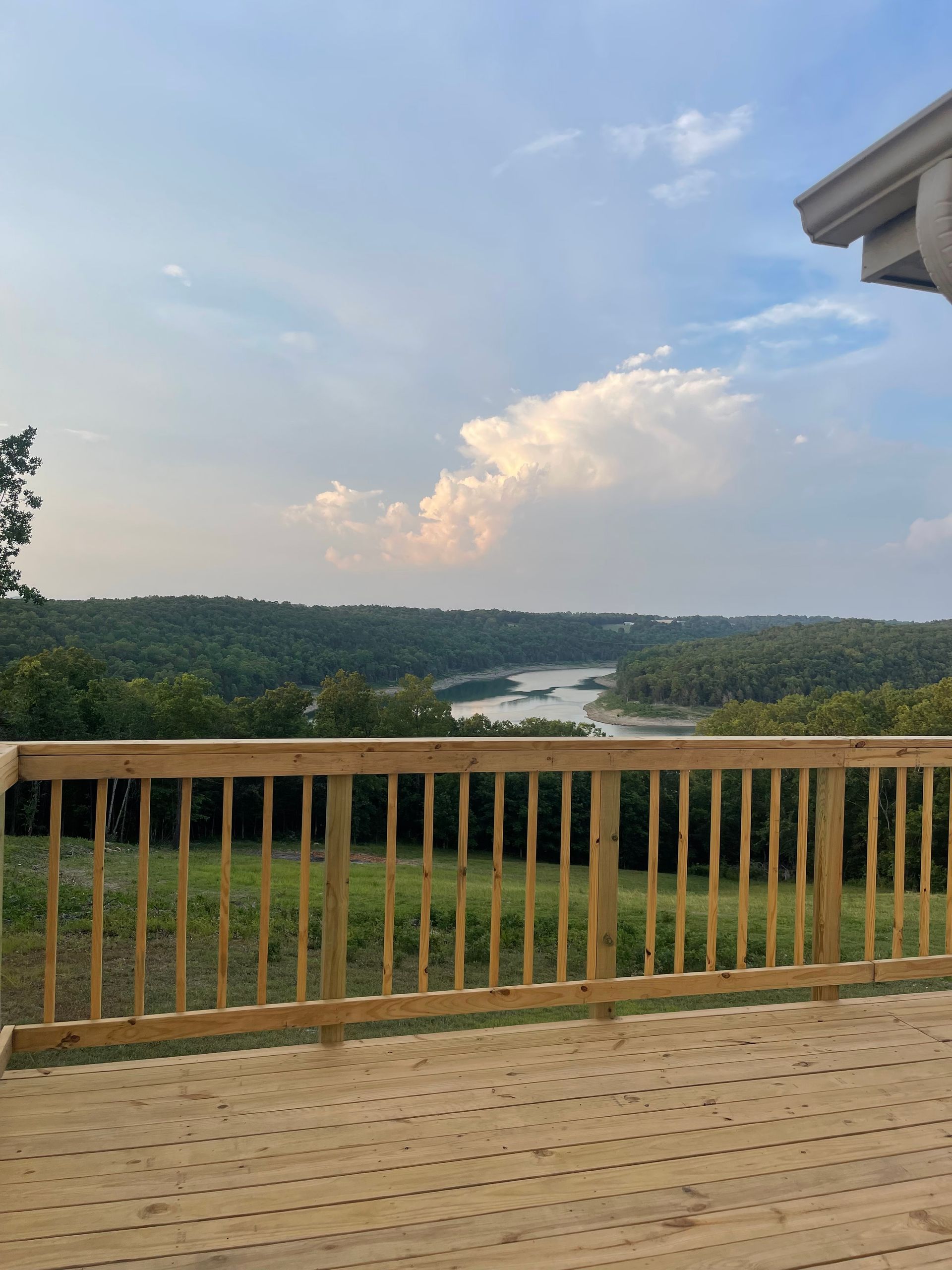 A view of a lake from a deck with a wooden railing