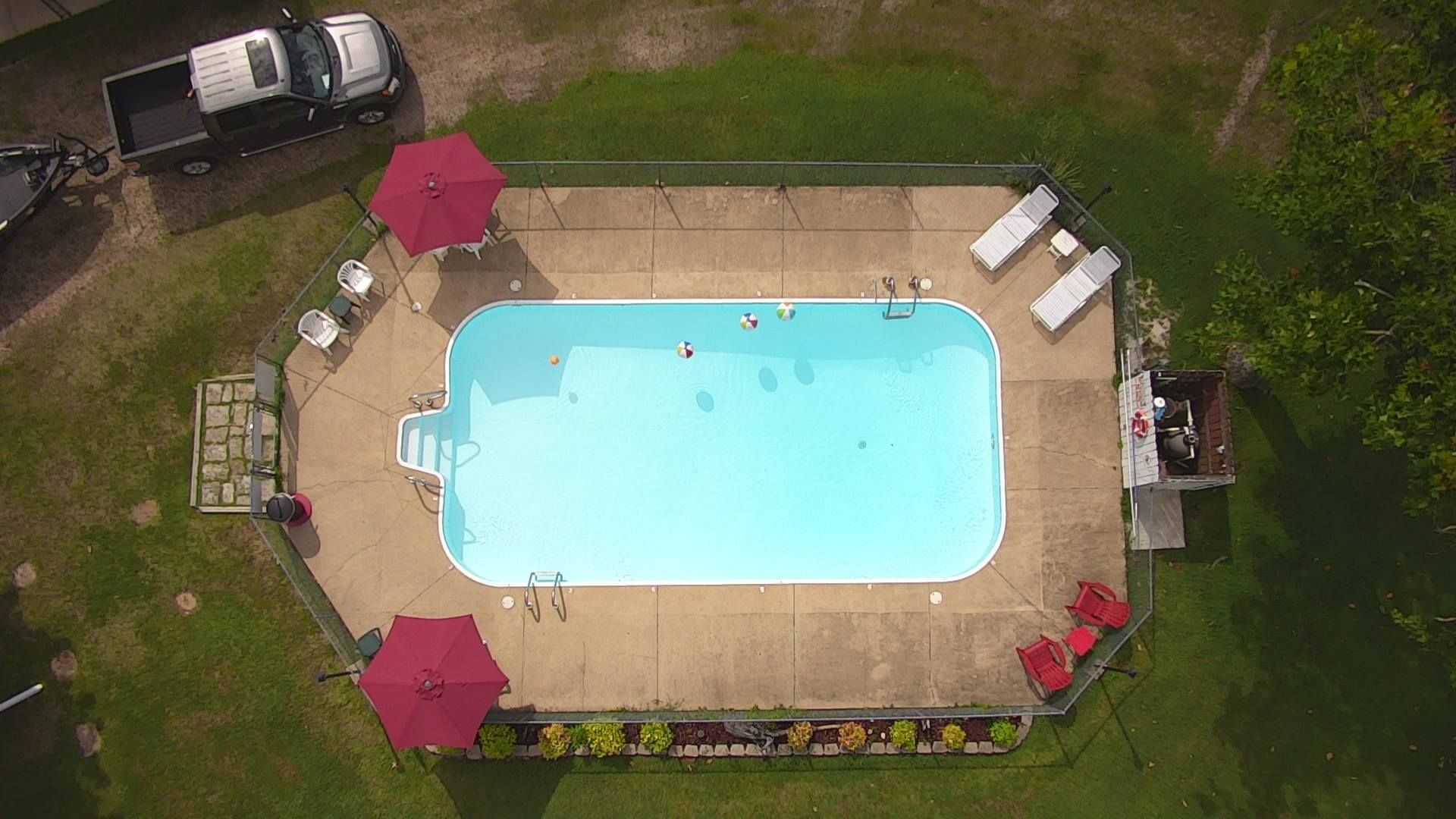 An aerial view of a large swimming pool surrounded by chairs and umbrellas.