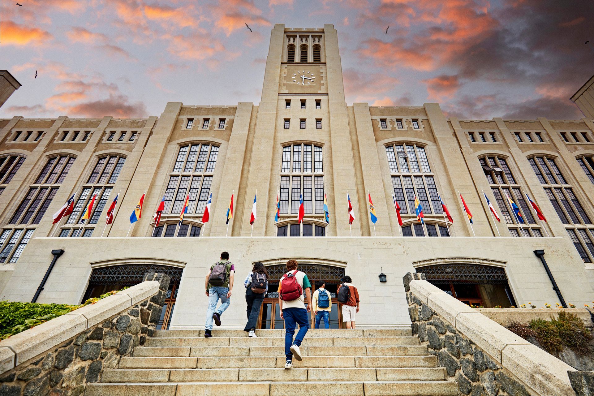 A group of students are walking up the stairs to a large building.