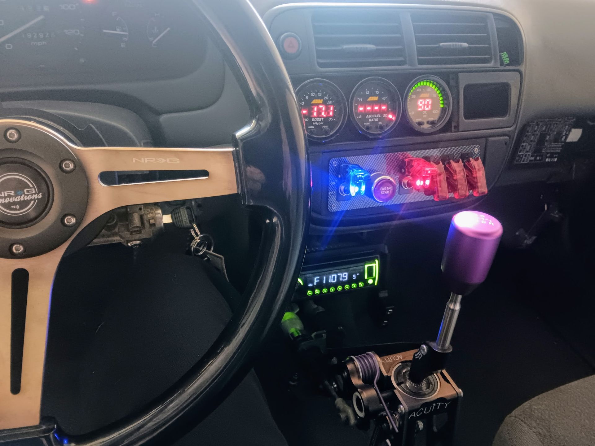 Interior car view with gauges, switches, and a modified gear shift.