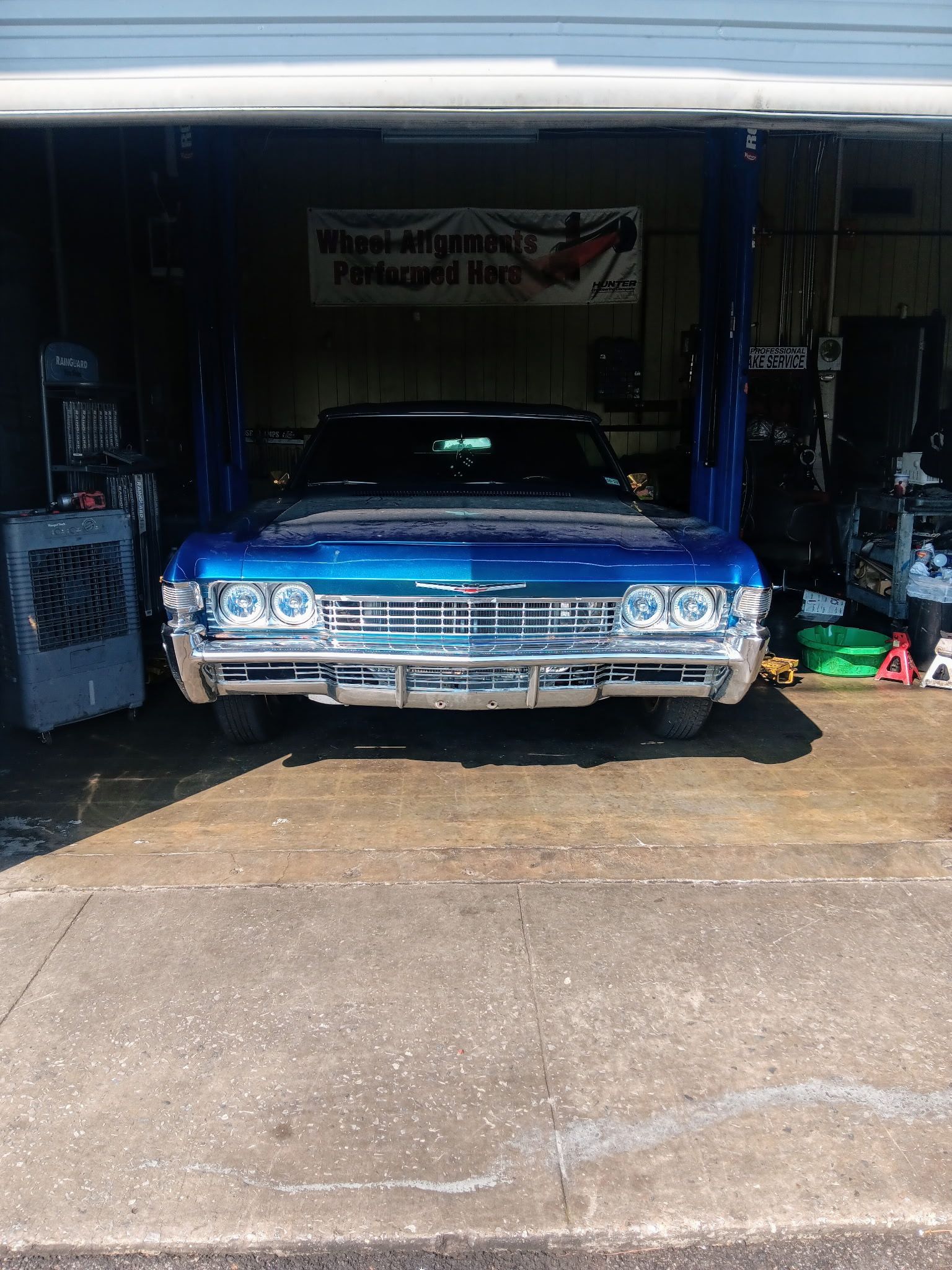 Blue classic car with gull-wing doors open in a garage.
