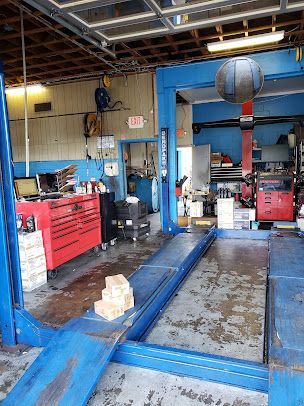 A car repair shop interior with a blue lift, red toolbox, and equipment.