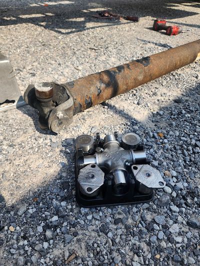 A rusty pipe is laying on the ground next to a cross joint.