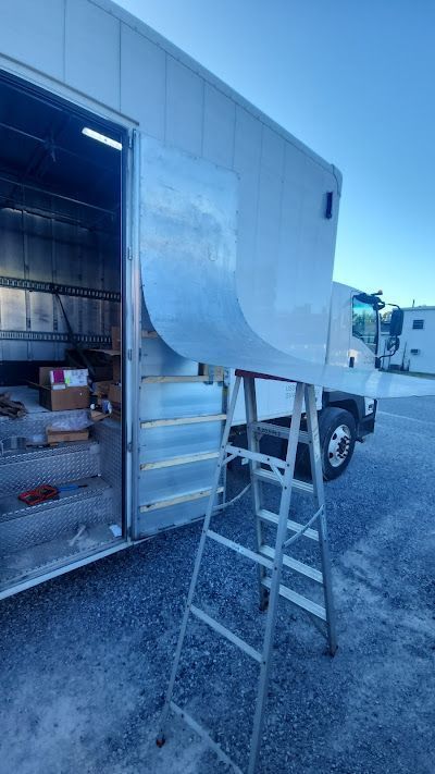 A ladder is sitting next to a white truck in a parking lot.