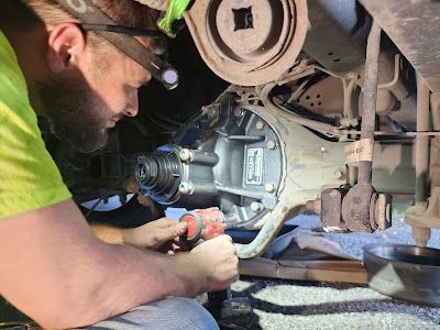 A man is working on the underside of a truck.