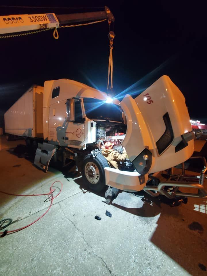 A white truck with the hood open is being worked on