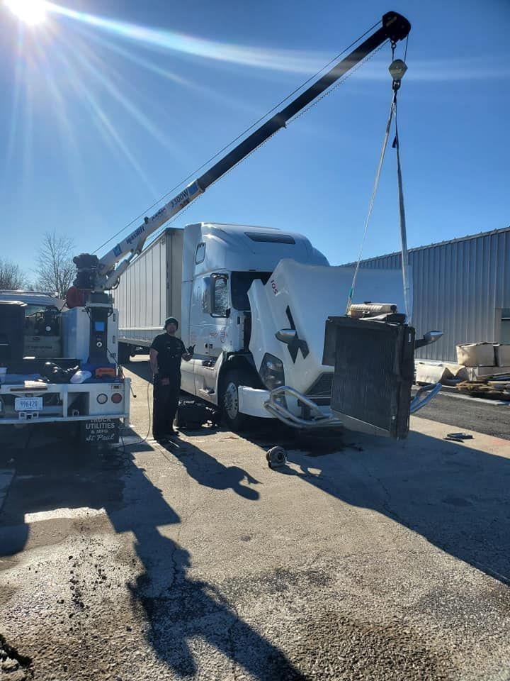 A truck is being towed by a crane in a parking lot.
