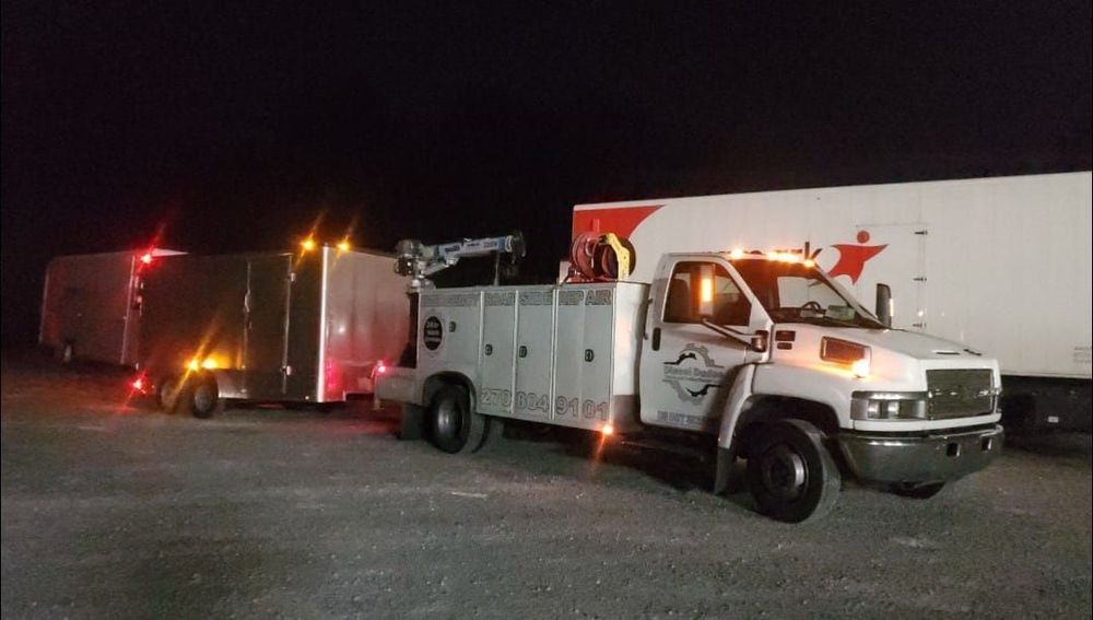 A white truck with a red star on the side is parked next to a white trailer