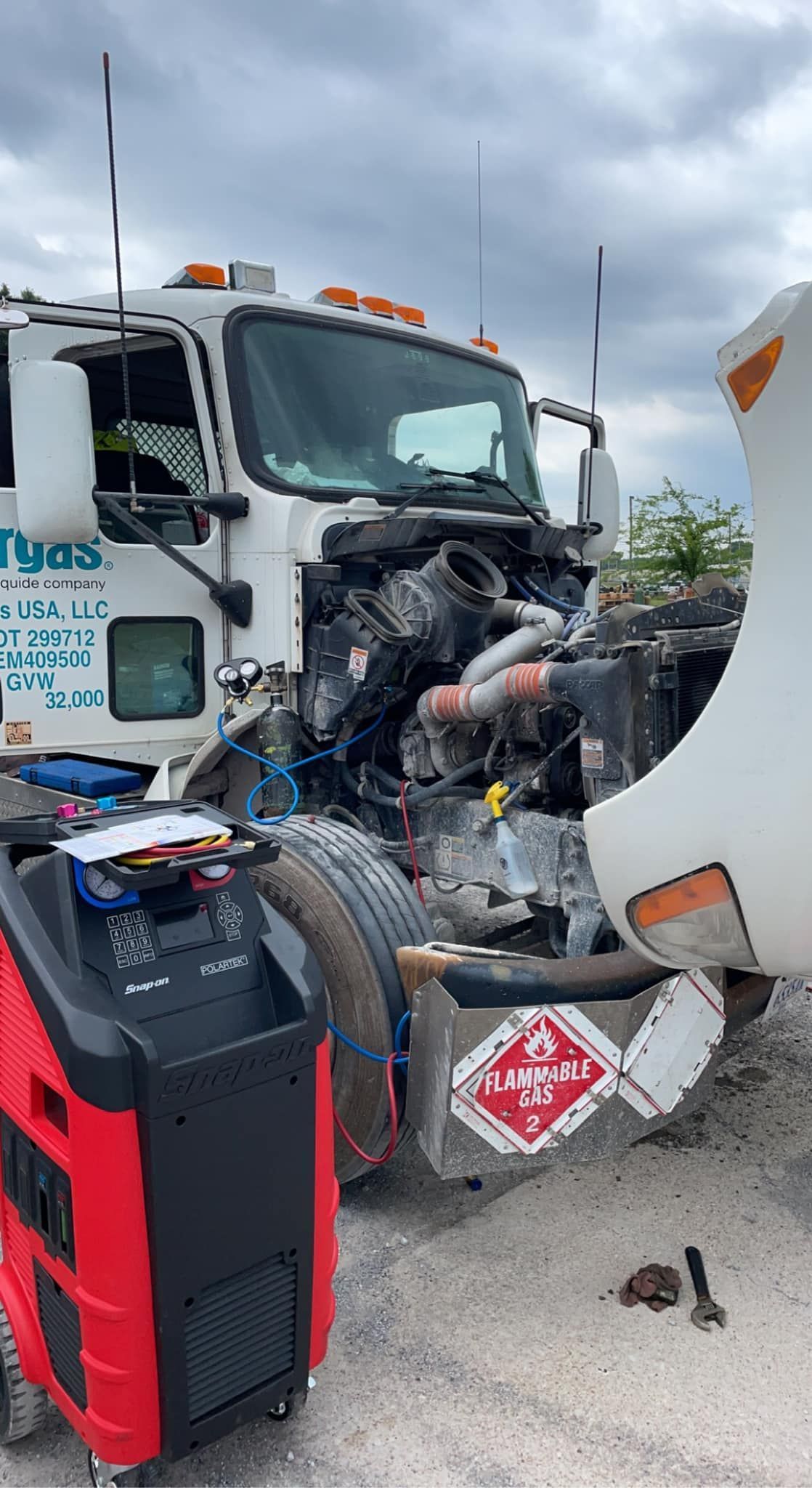 A truck with its hood up is being worked on by a mechanic.