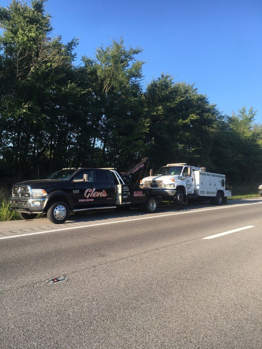 Two tow trucks are parked on the side of the road.