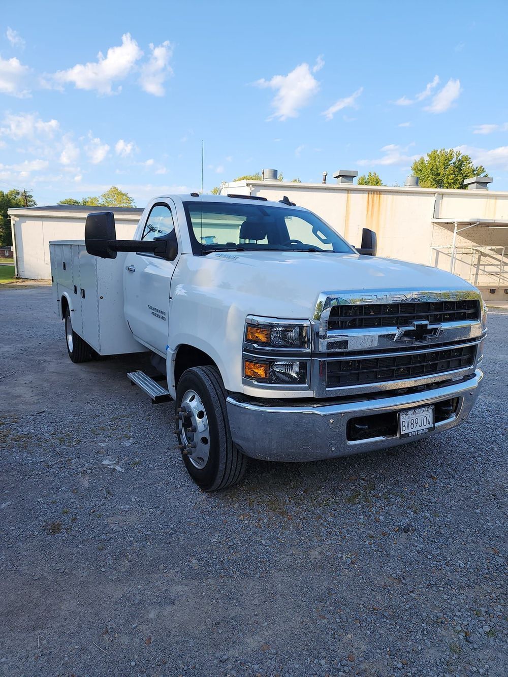 A white truck is parked in a gravel lot.