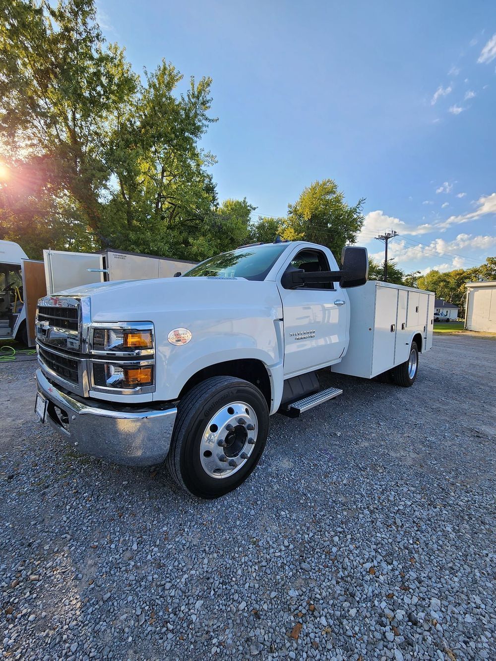 A white truck is parked in a gravel lot.