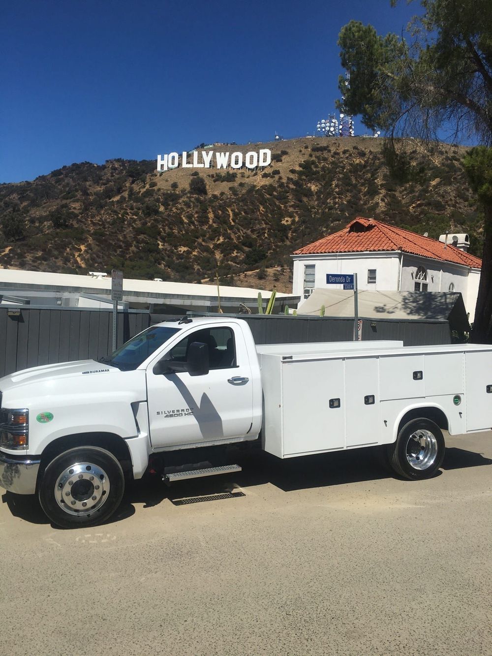 A white truck is parked in front of the hollywood sign