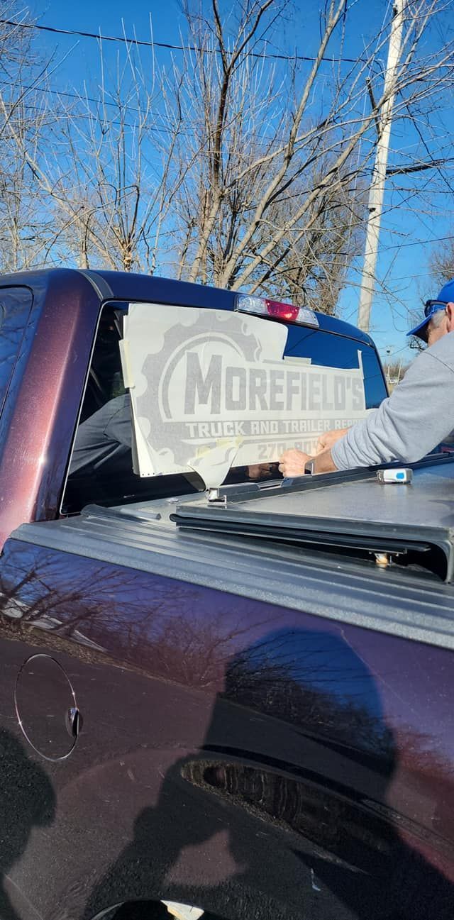 A man is working on the back window of a truck.
