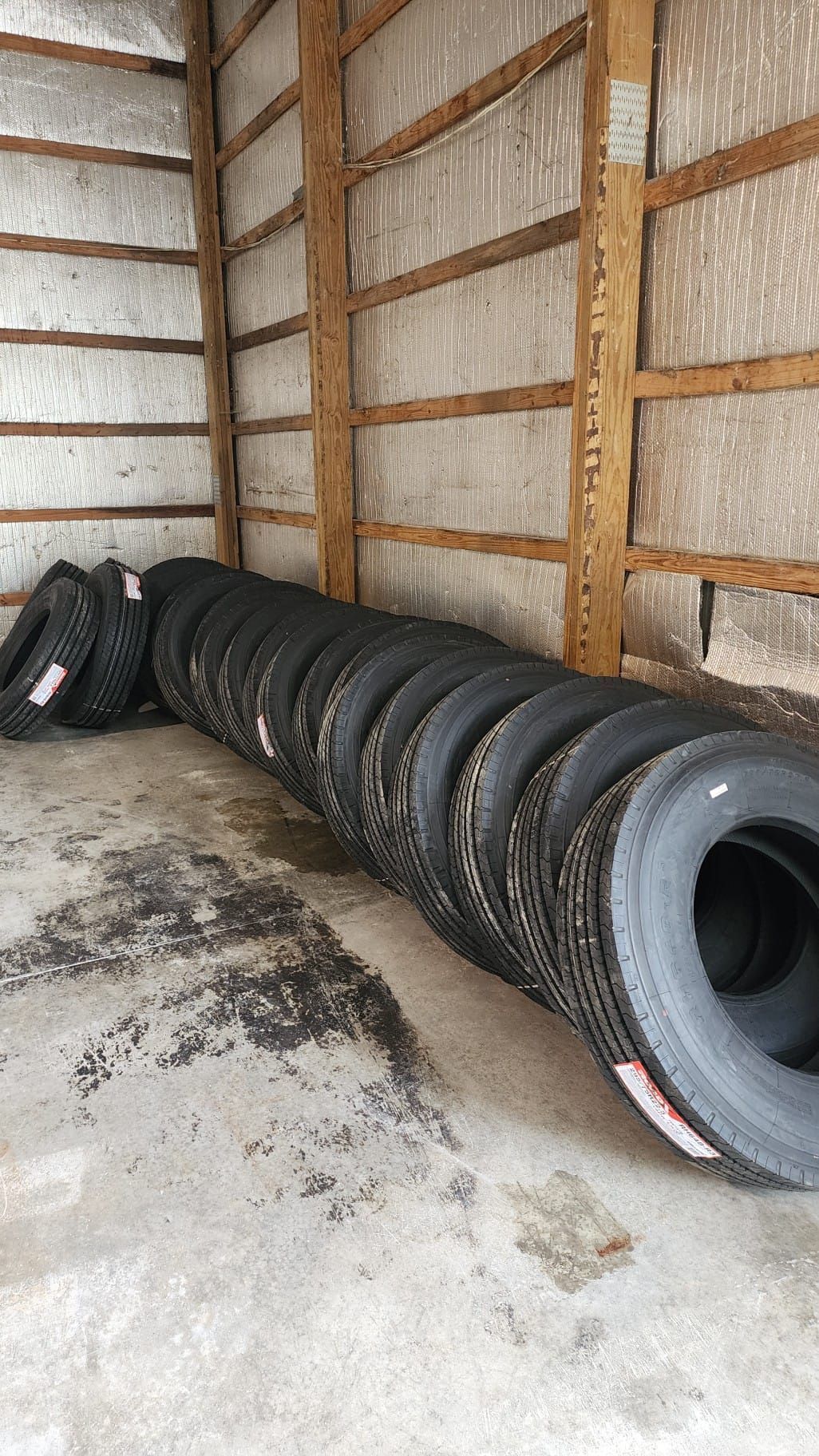 A bunch of tires are stacked on top of each other in a garage.