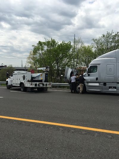 A semi truck is being towed by a tow truck on the highway.